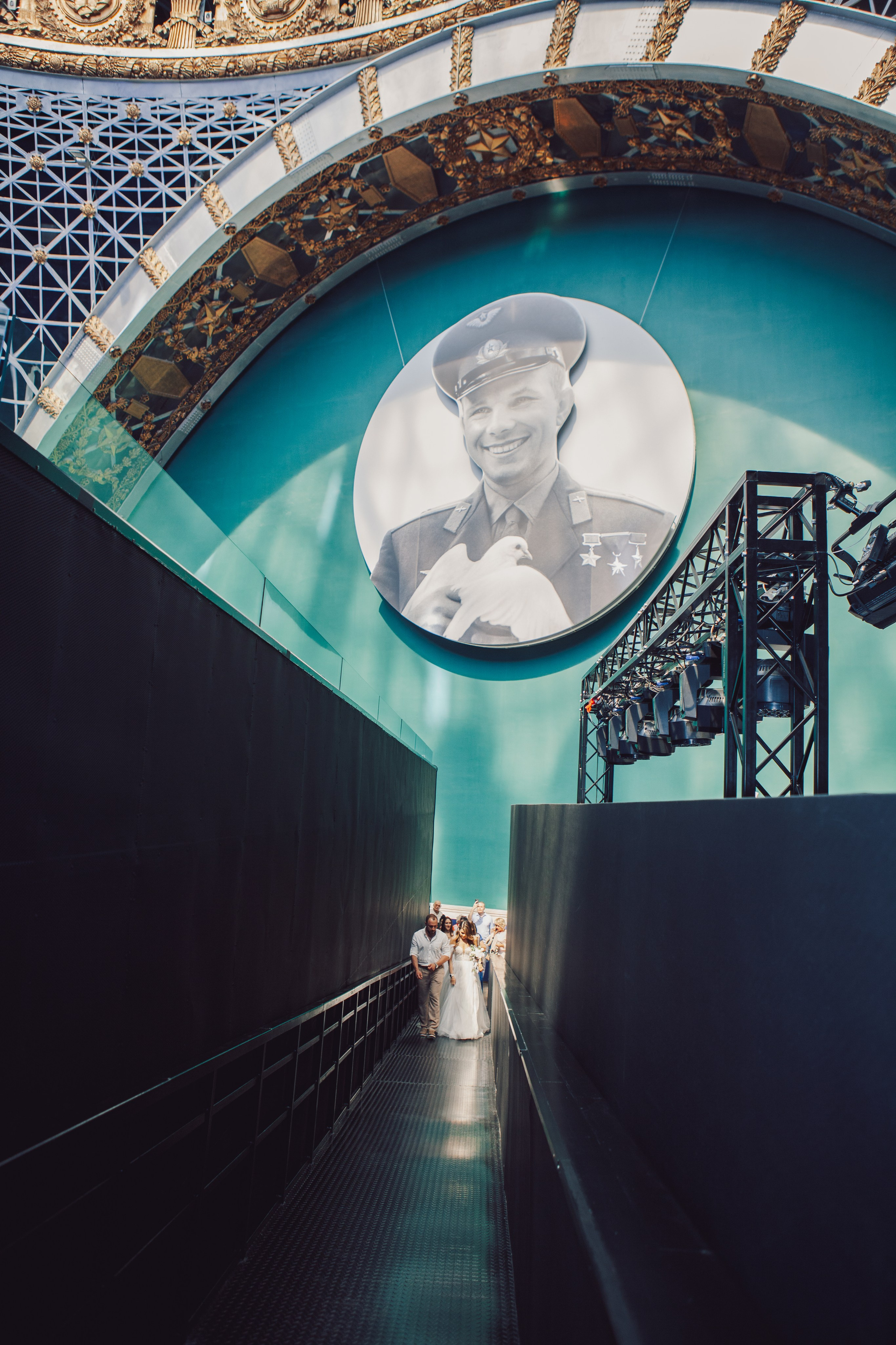 молодожены идут на фоне космонавта Гагарина в павильоне космонавтики и авиации №34