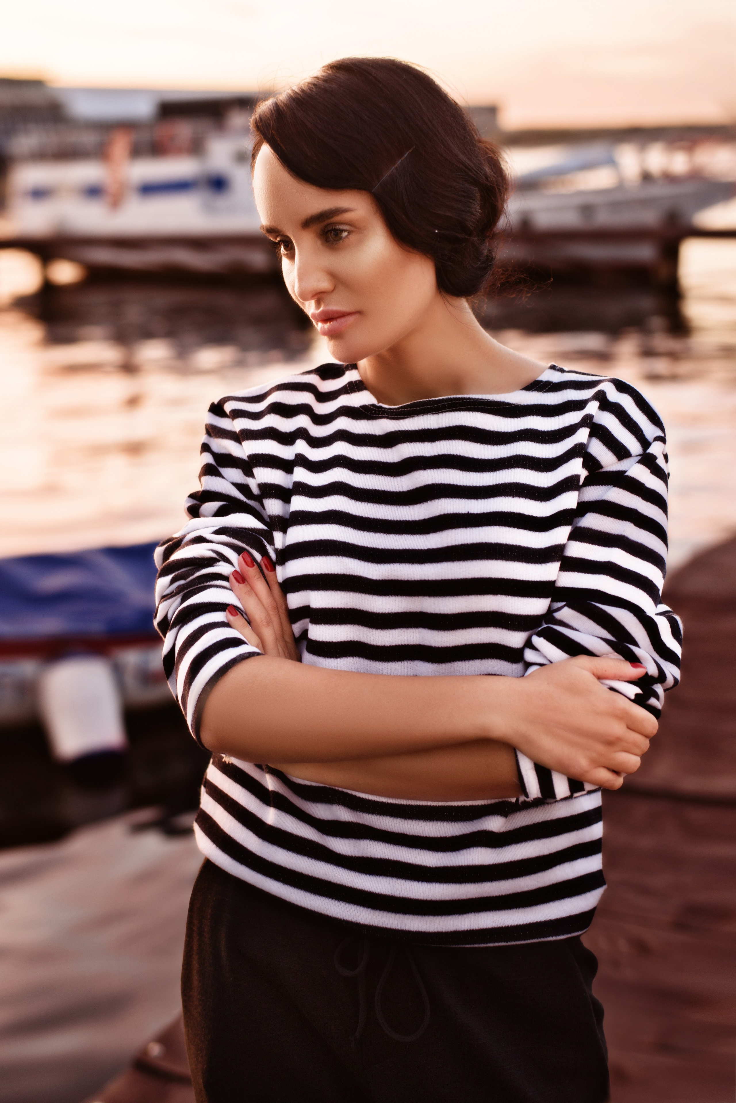 Фотосессия девушки в тельняшке на фоне заката у воды на причале