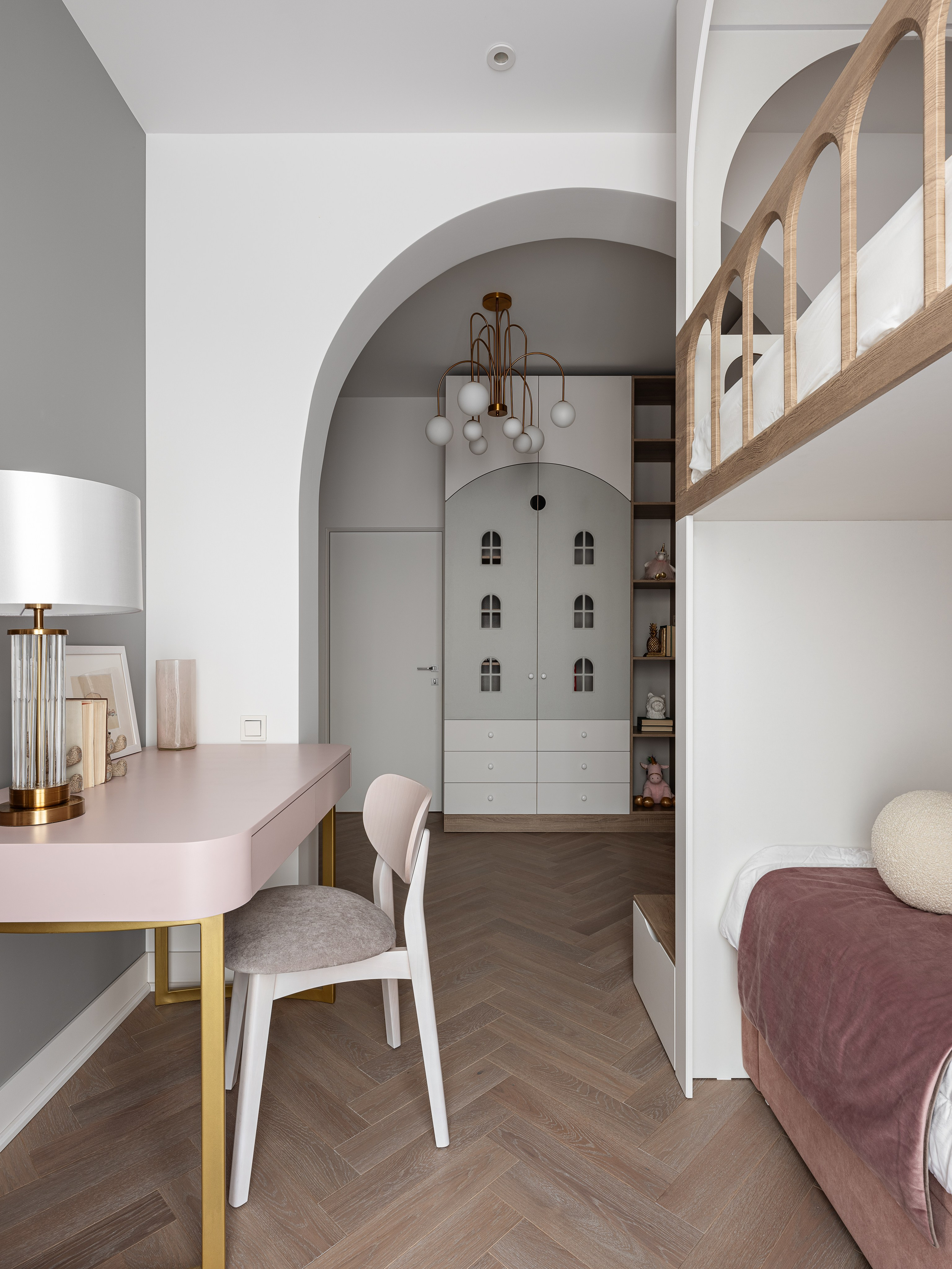 Просторная детская комната с розовым письменным столом на золотых ножках, современным креслом, встроенными шкафами с арочными фасадами и мягкой кроватью, оформленная дизайнером Василиссой Бачевой, стилистом Натальей Якушевой и сфотографированная Сергеем Денисенко.