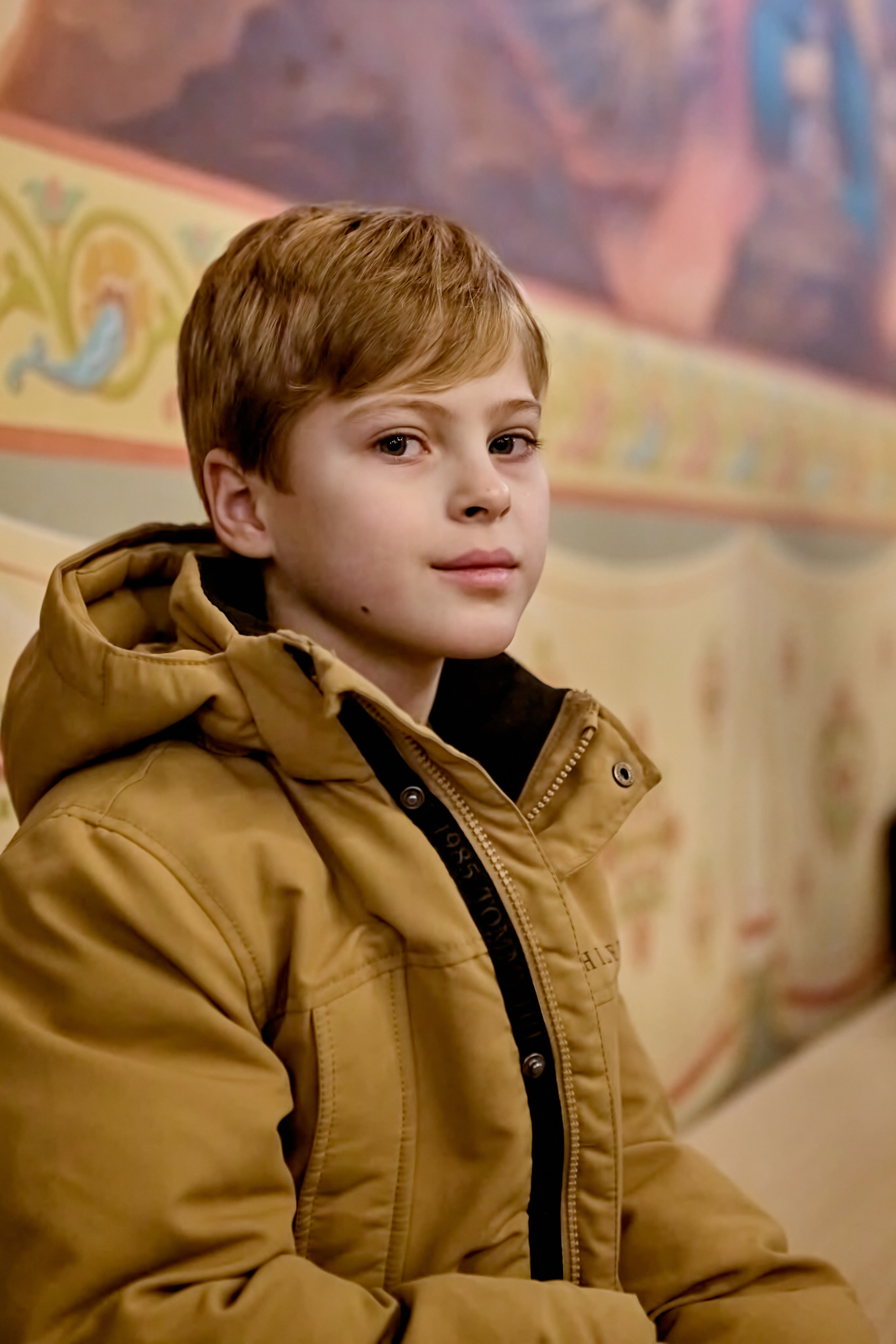 Мальчик в храме в куртке после службы ждет маму