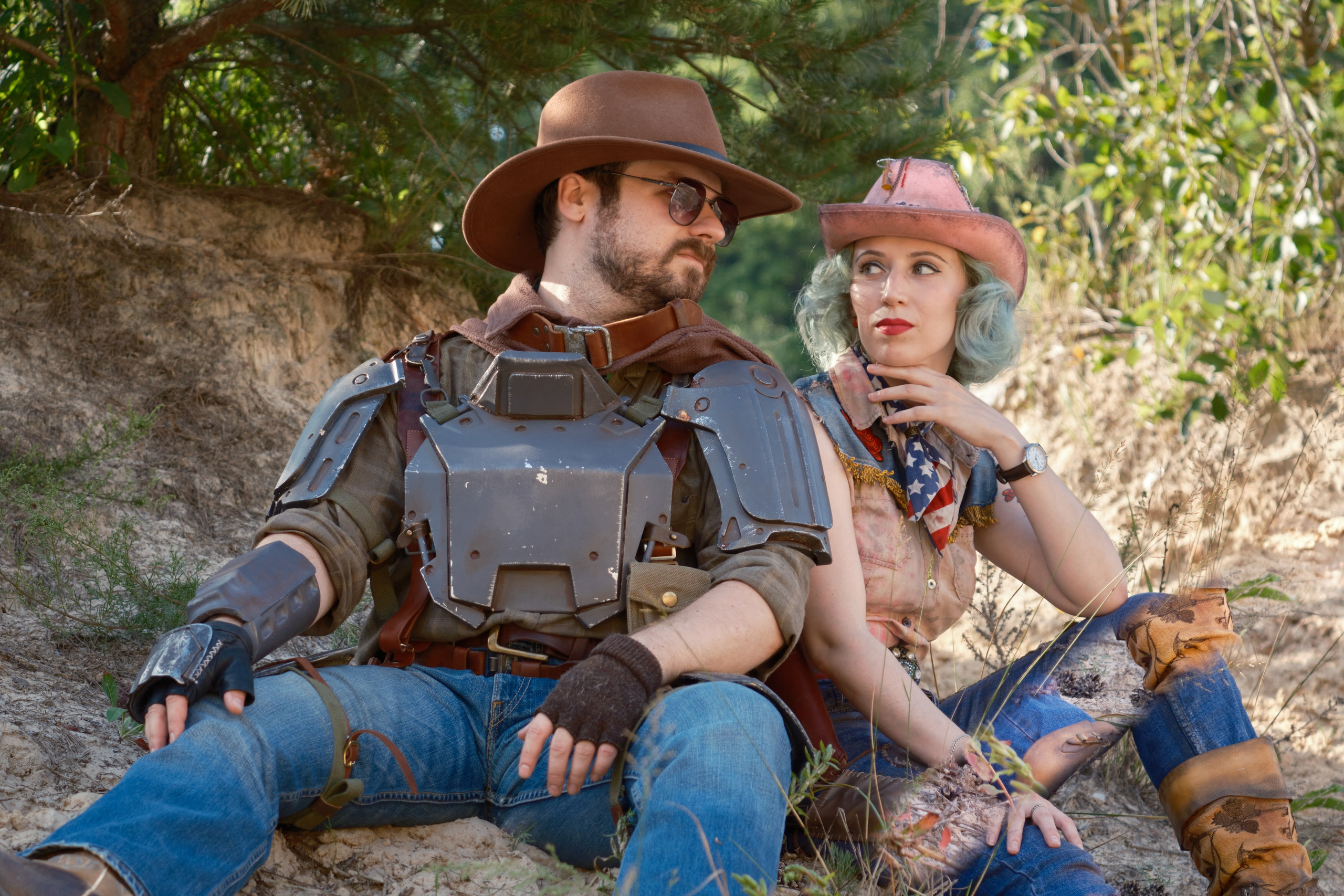 Мужчина и девушка в ковбойских шляпах сидят на земле