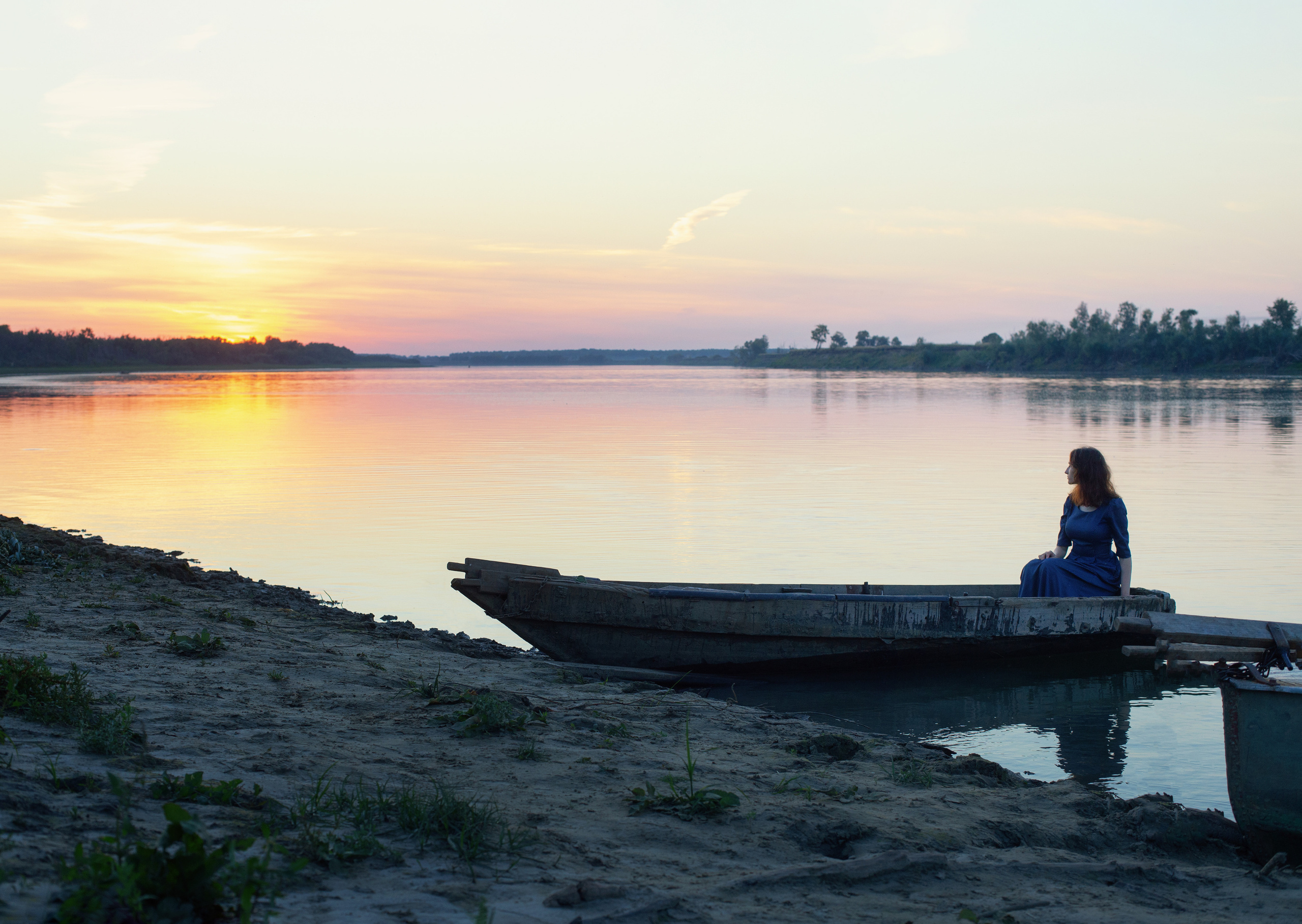 закатное небо и в лодке сидит одна девушка на речке.