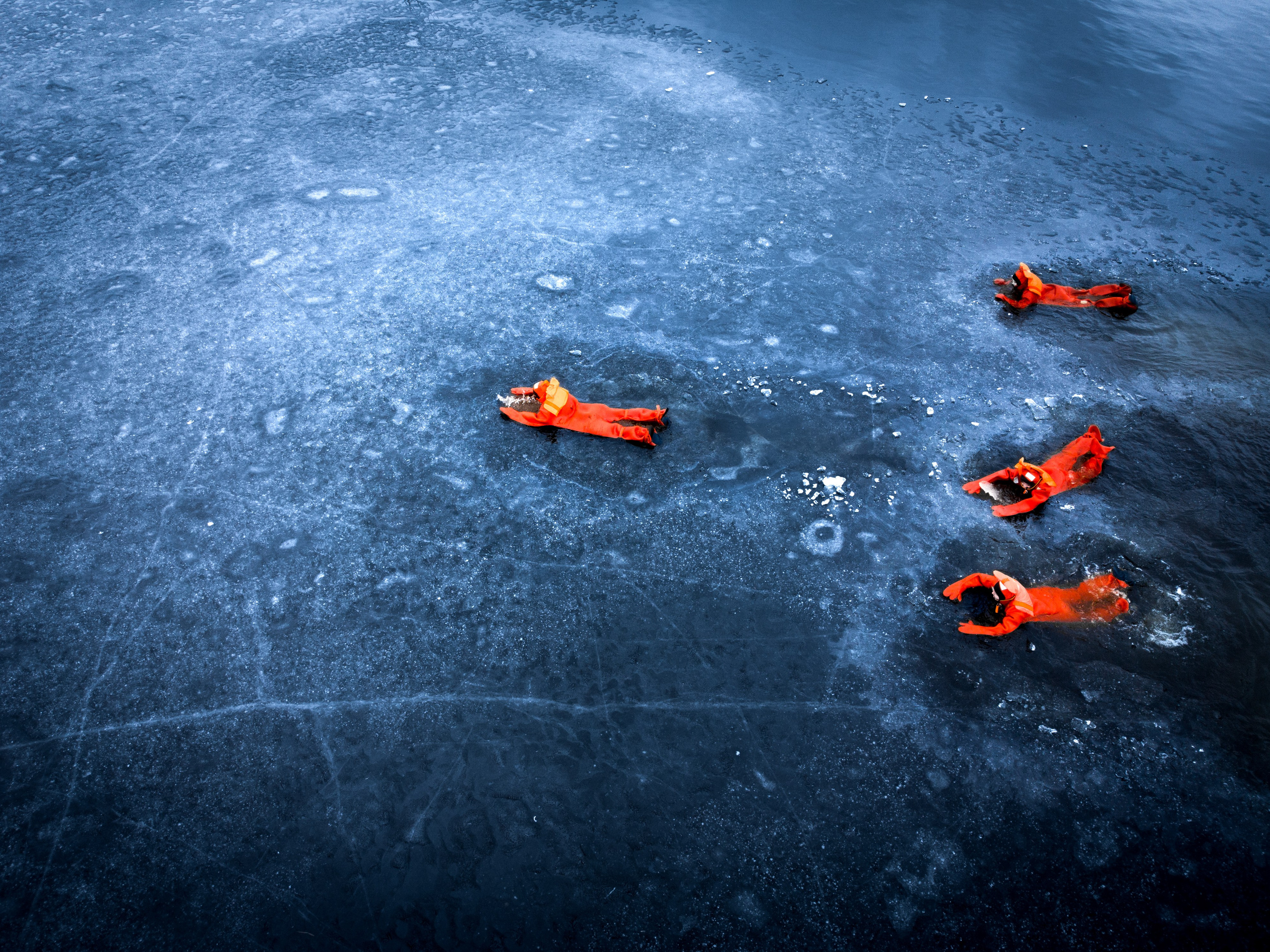Люди купаются среди льдин, в спасательных оранжевых термо костюмах, айс флоатинг Ярославль