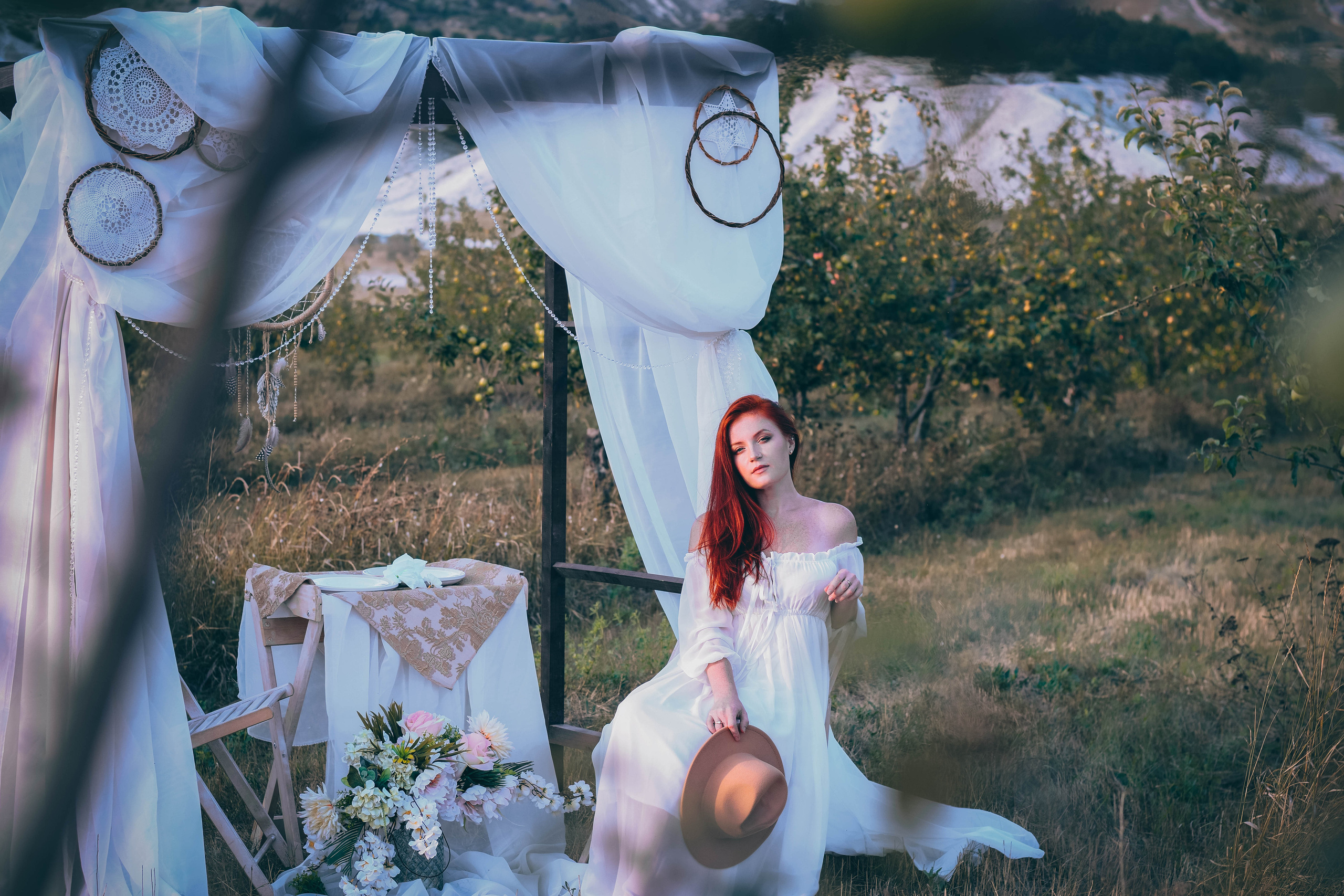 Невеста в белом платье на фоне яблоневого сада на выездной церемонии