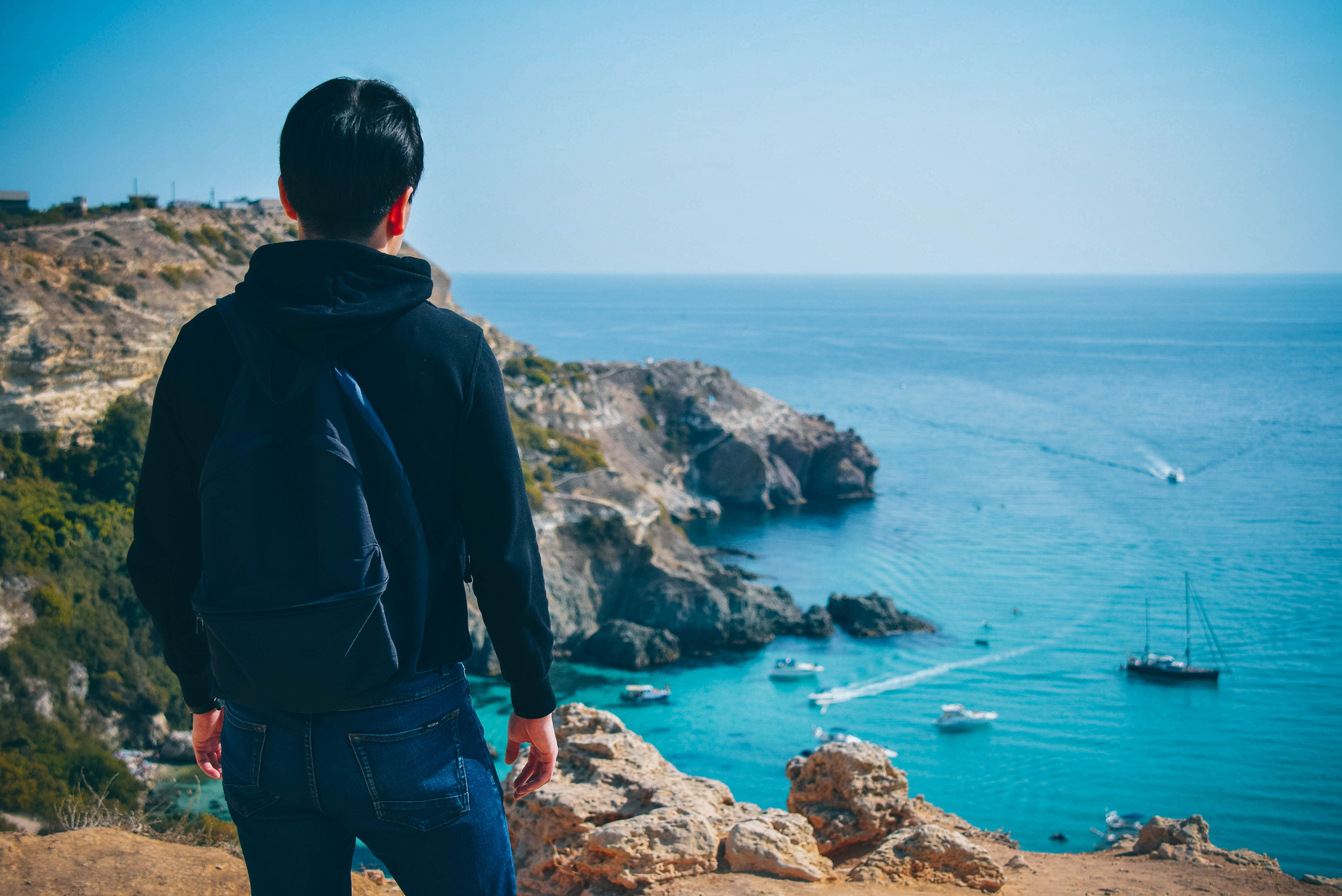 travel фотосъемка молодого человека над обрывом скал и морем на пляже Баунти в Севастополе