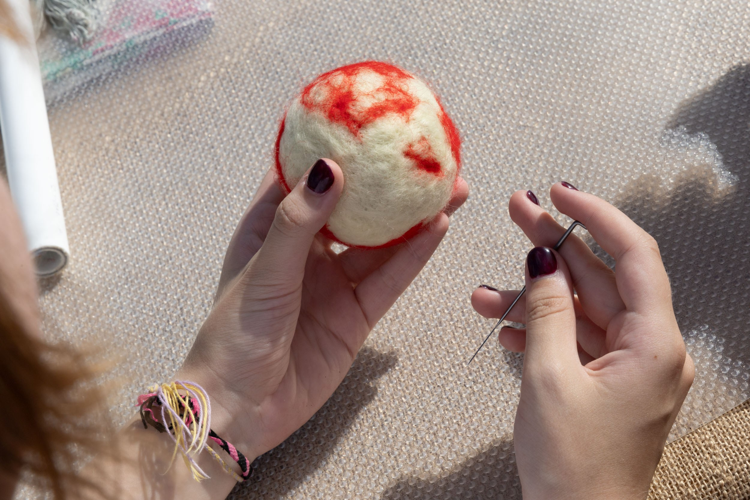 Бело-красный войлочный шарик в женских руках.