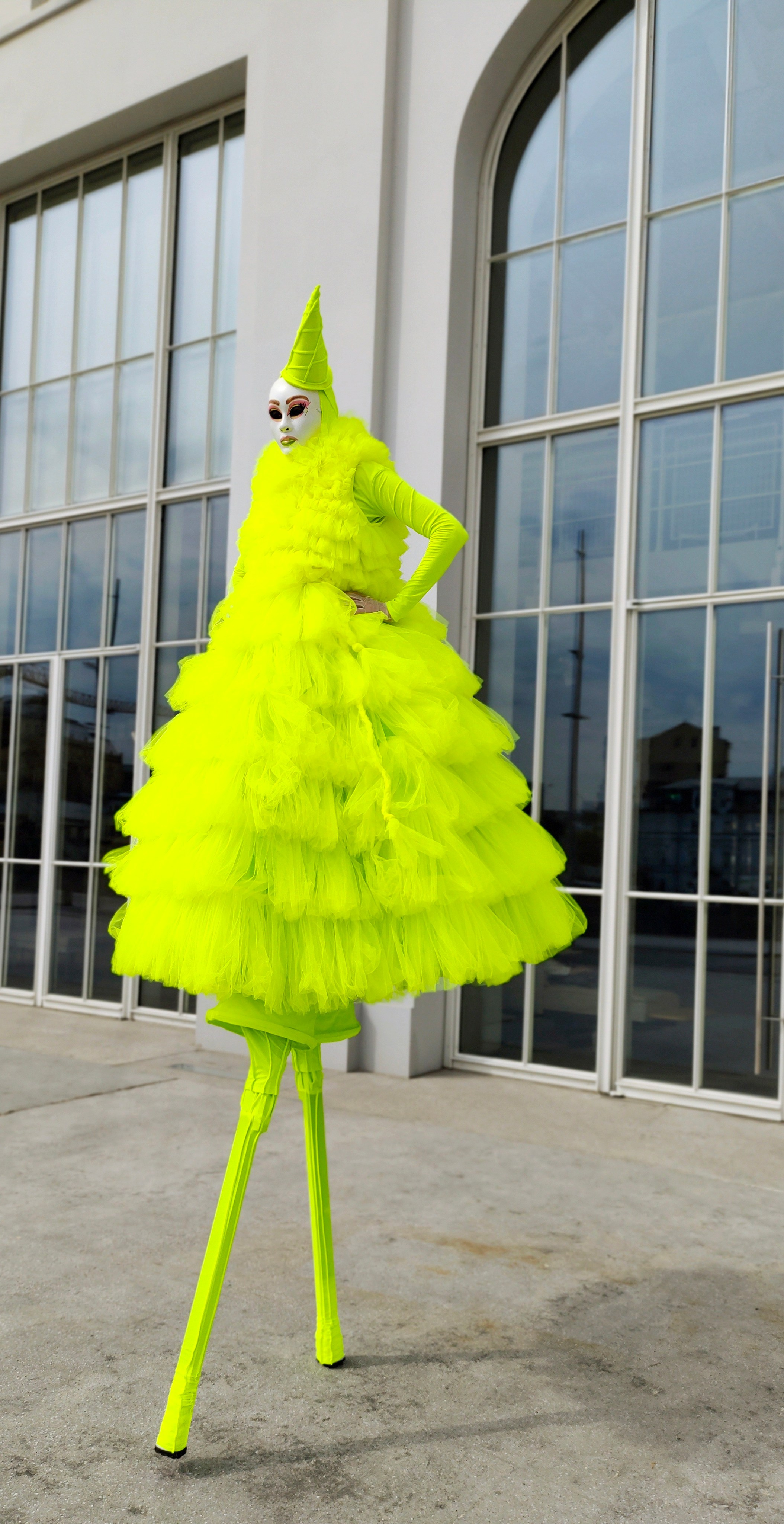 Артист на ходулях позирует фотографу у белого здания на велком