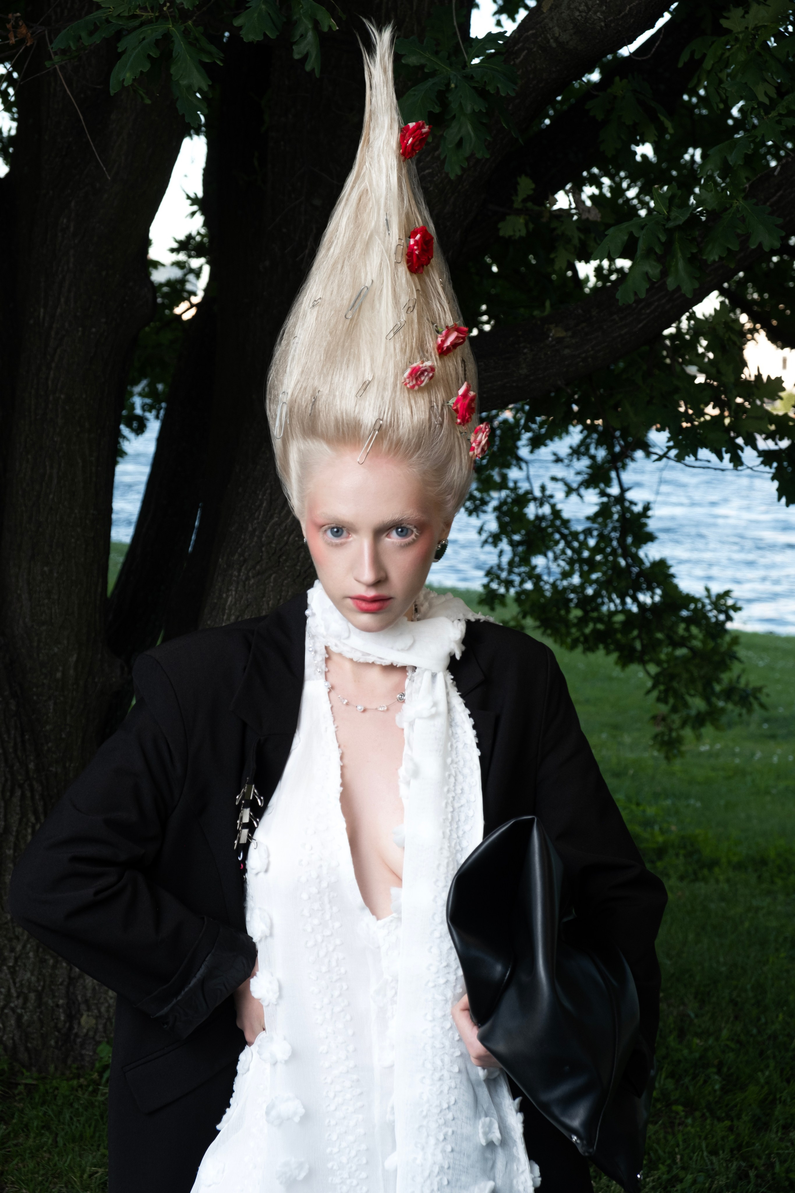 Девушка модель блондинка с креативной прической стоит на природе