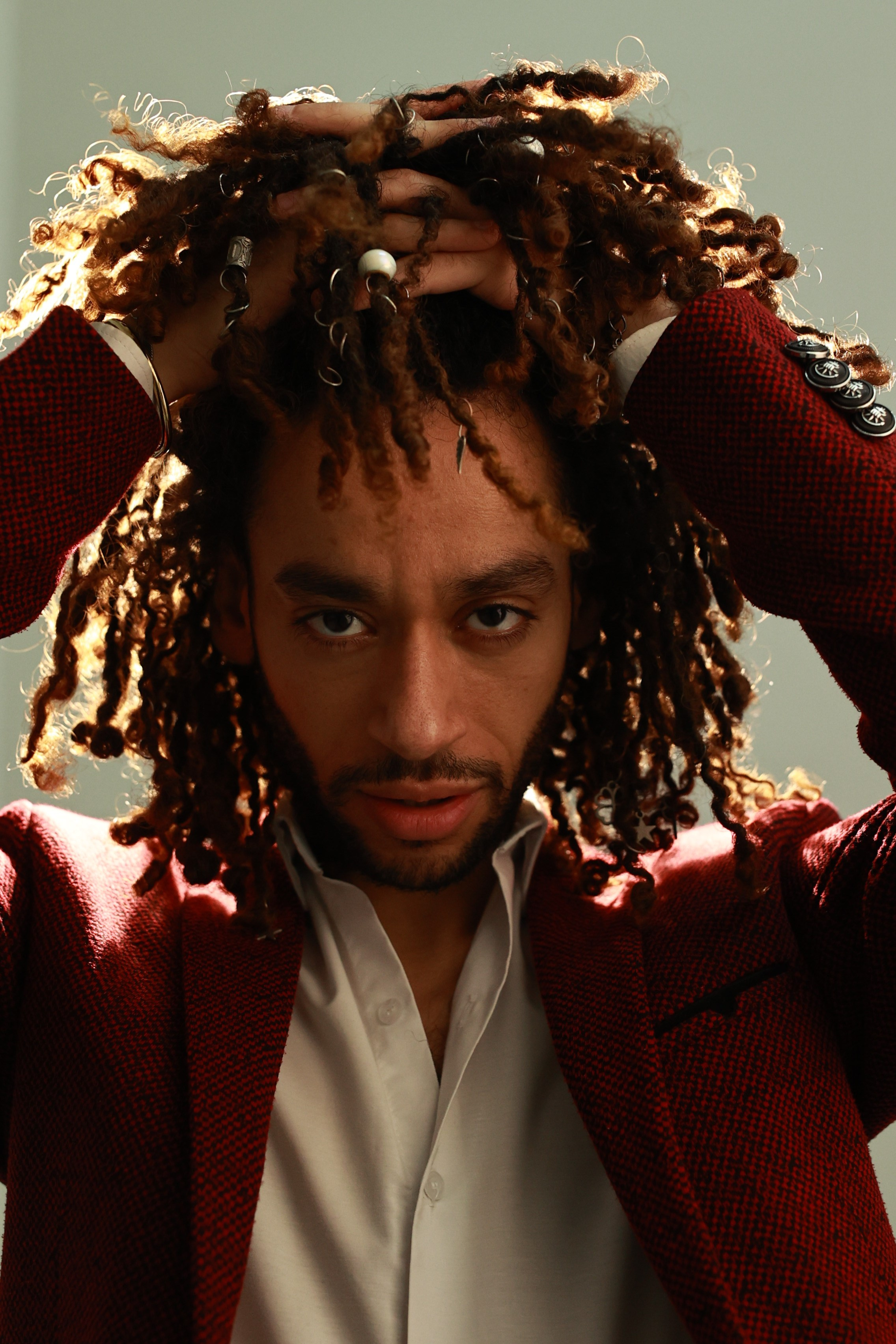 Потрет темнокожего парня с длинными кудрявыми волосами в красном пиджаке