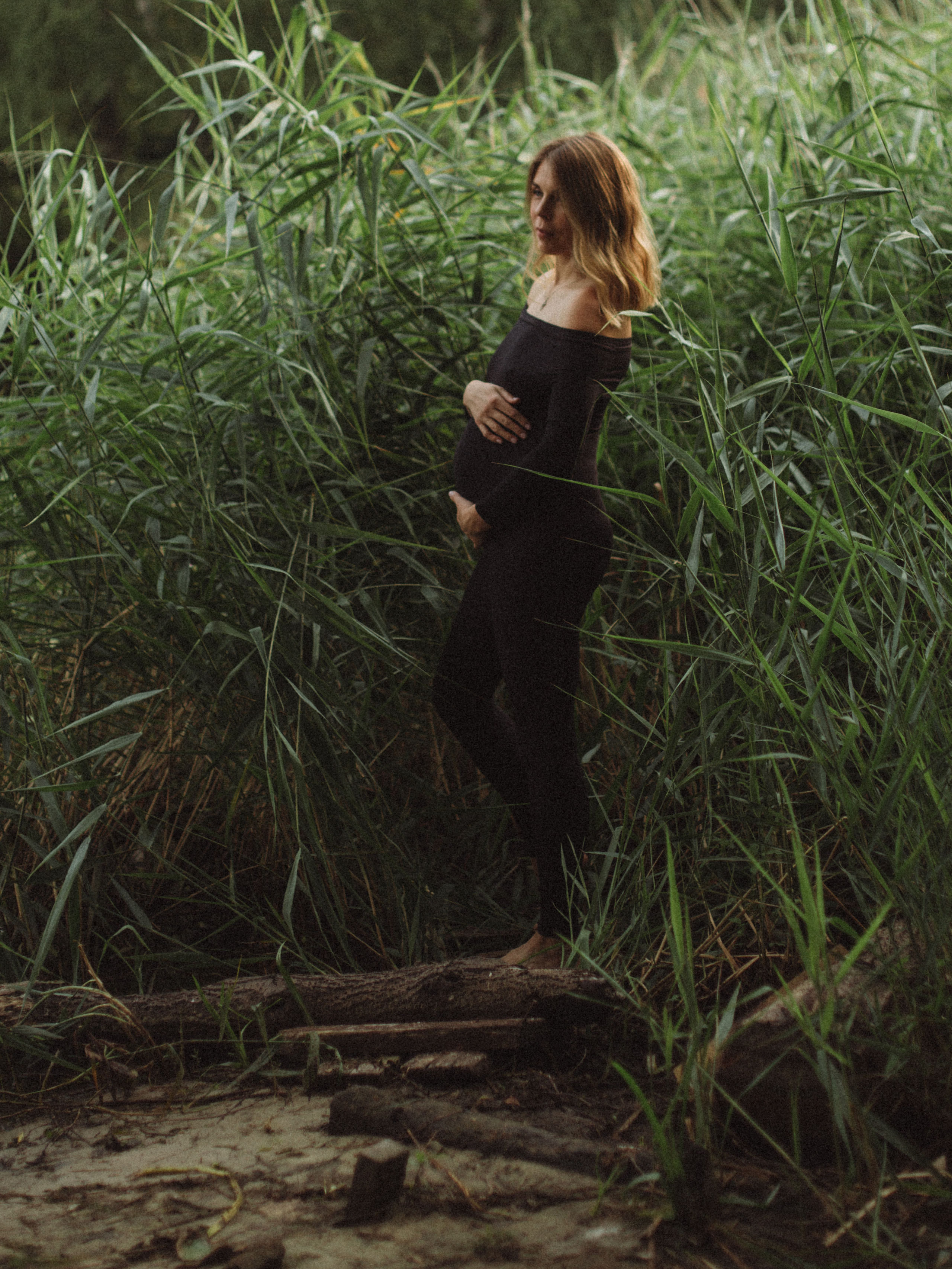 беременная девушка на берегу реки высокой траве