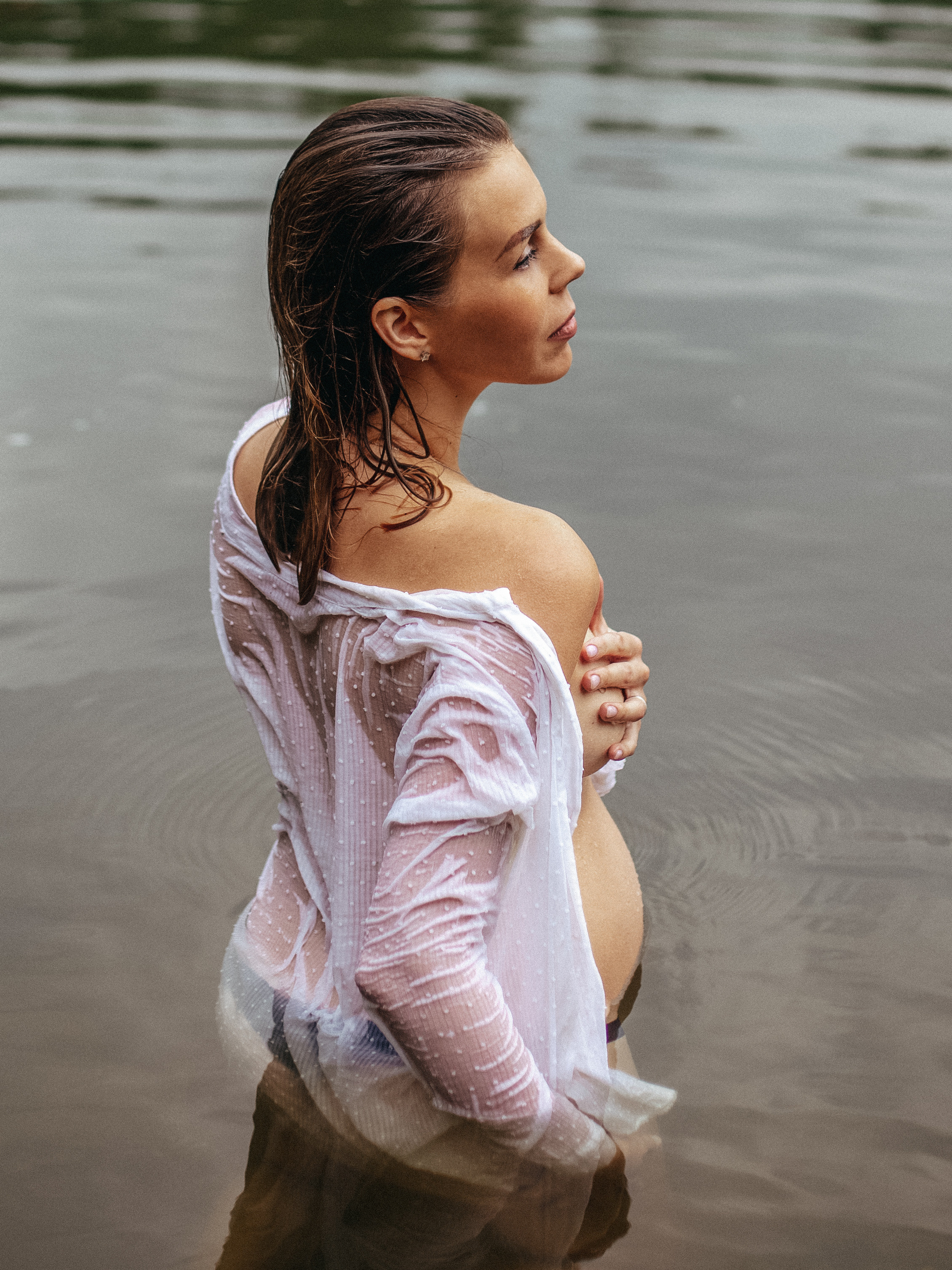 беременная девушка в мокрой белой рубашке в реке