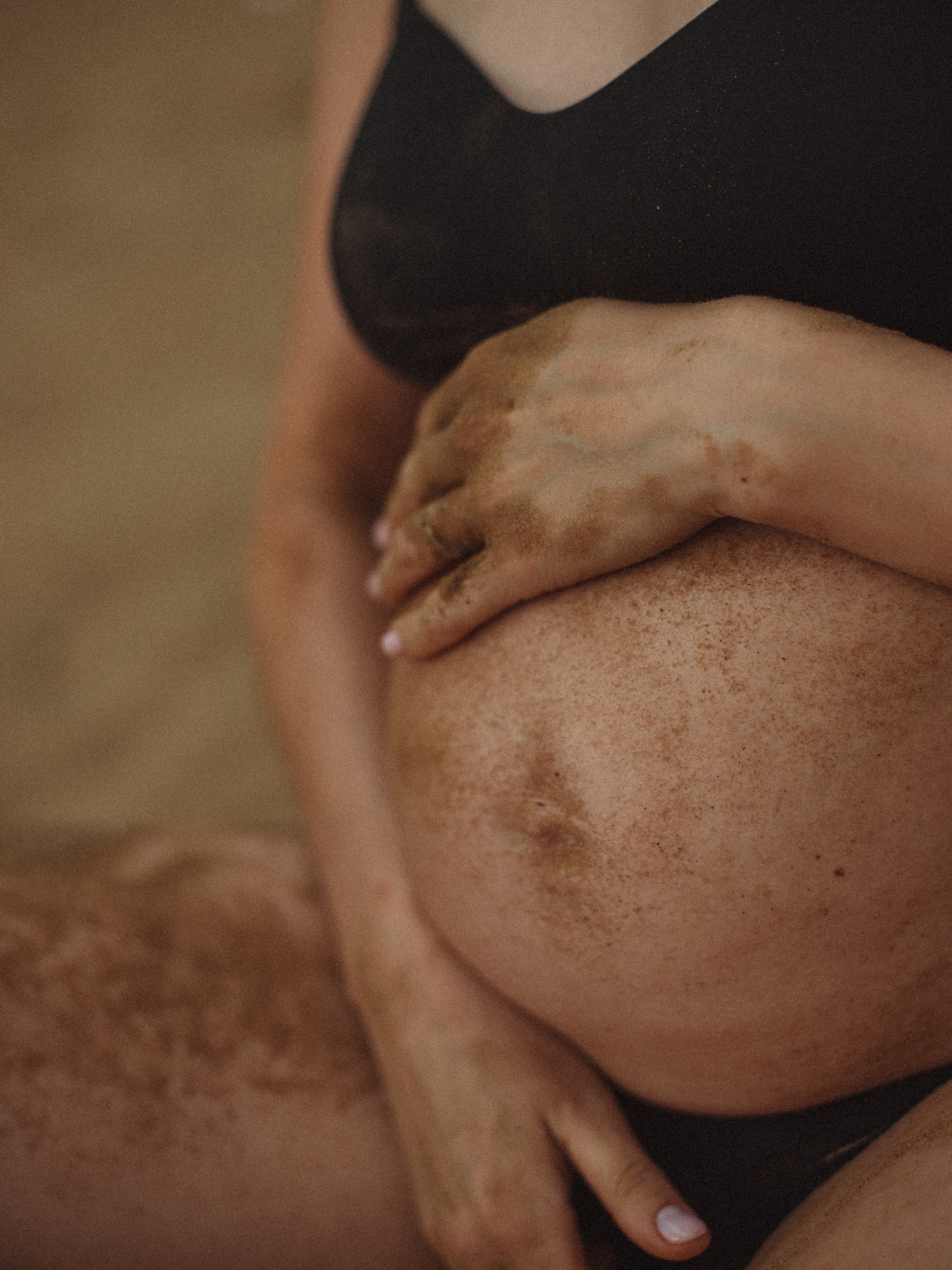 живот беременной девушки в песке