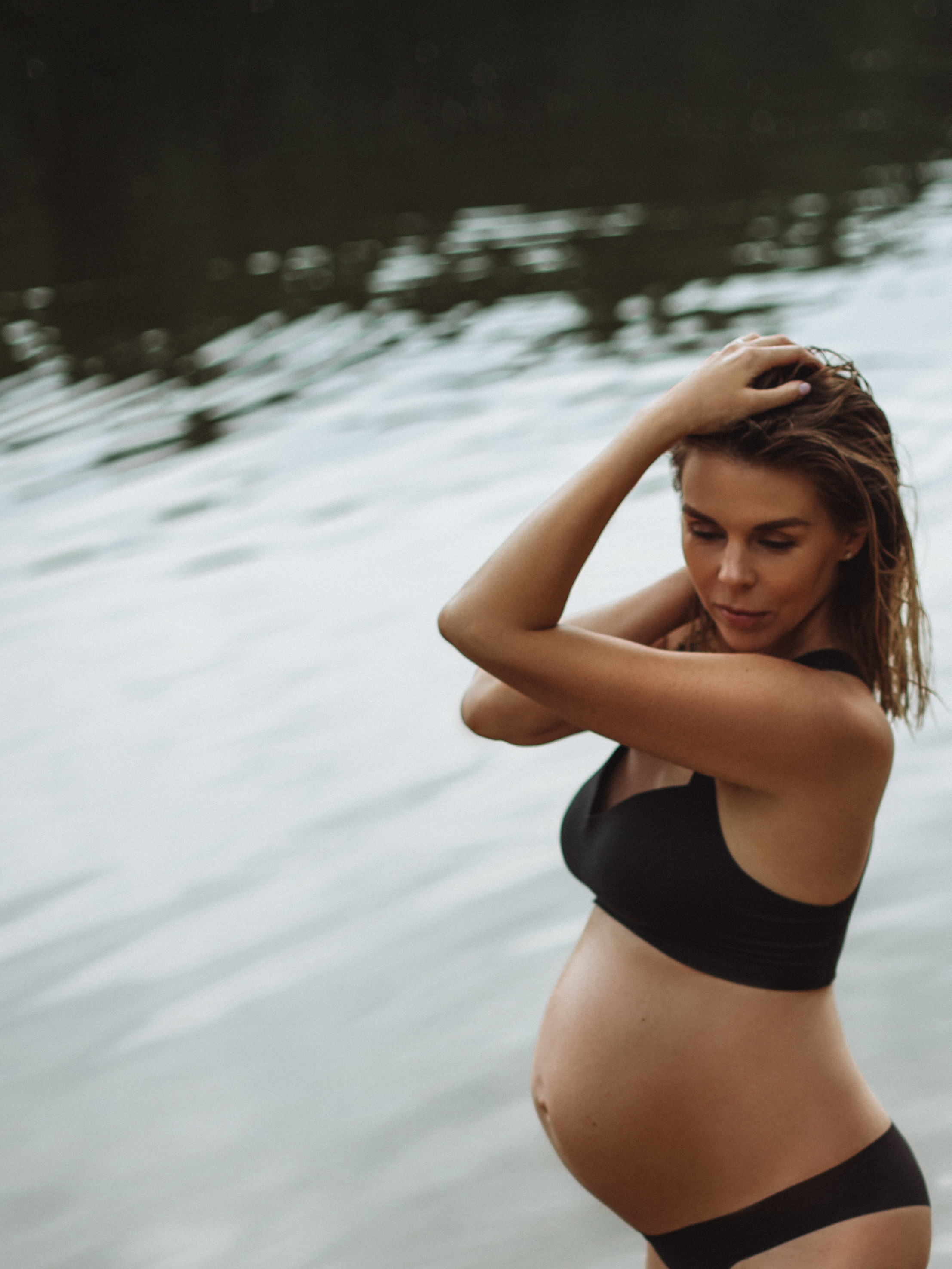 беременная девушка в изящном черном белье на берегу реки