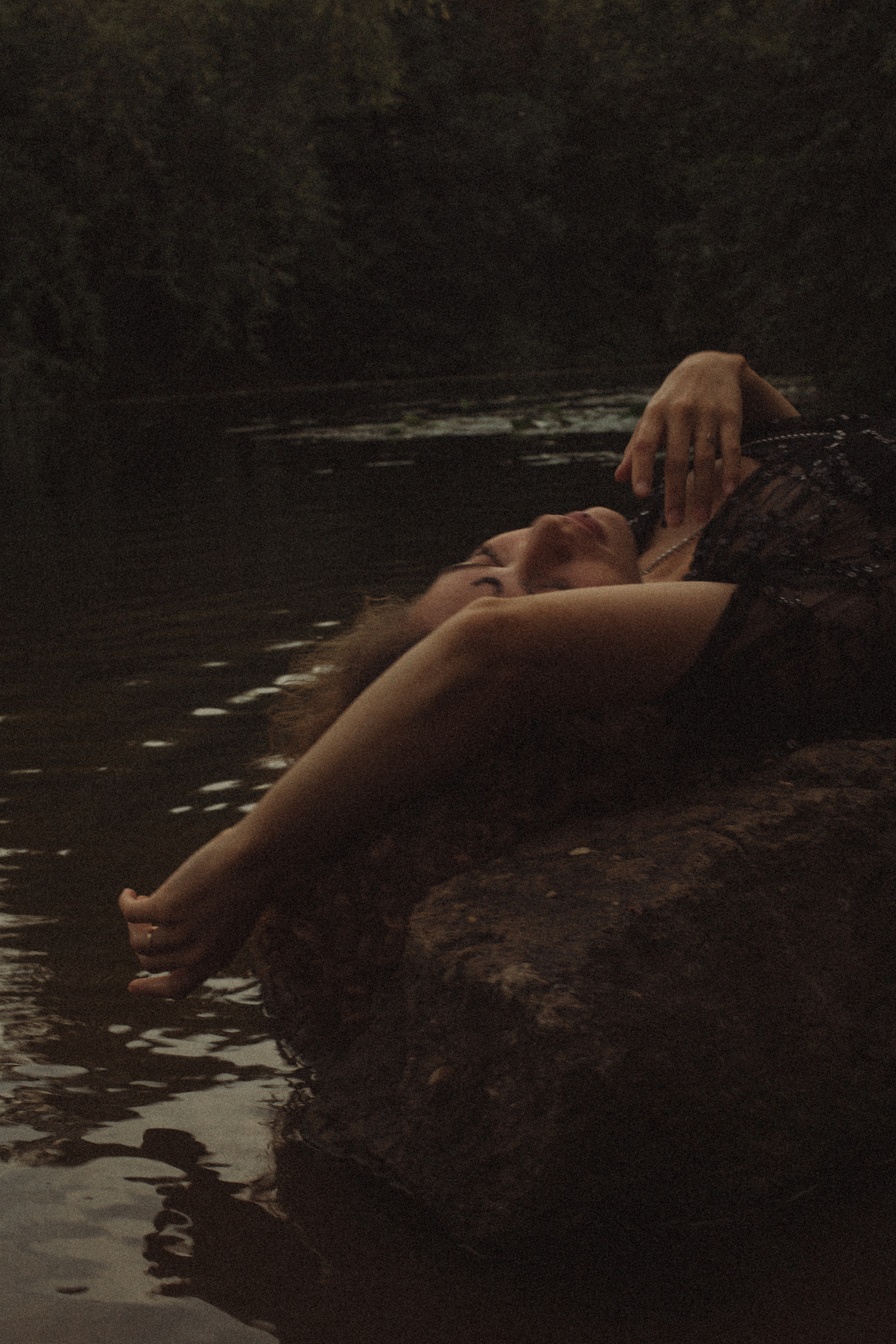 лежащая на камне в воде девушка в красивом черном белье