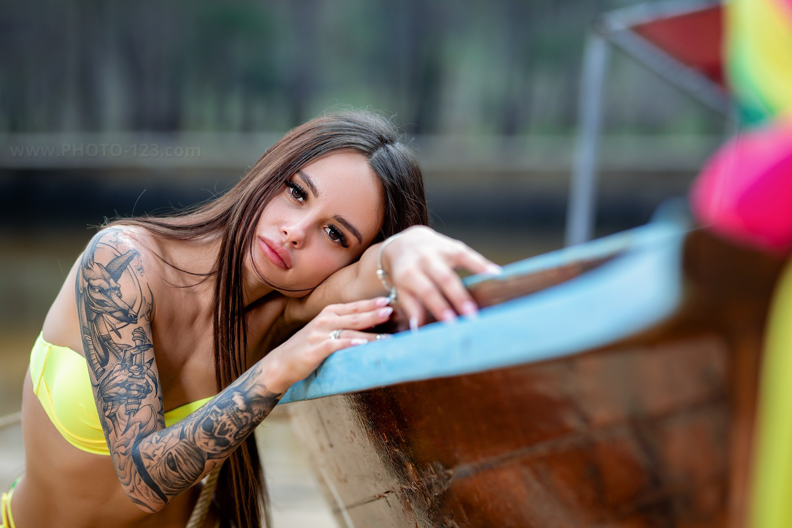 Lifestyle portrait photoshoot in Phu Quoc, Vietnam, professional photographer capturing tattooed female model in yellow bikini, close-up natural light portrait by the water with shallow depth of field
