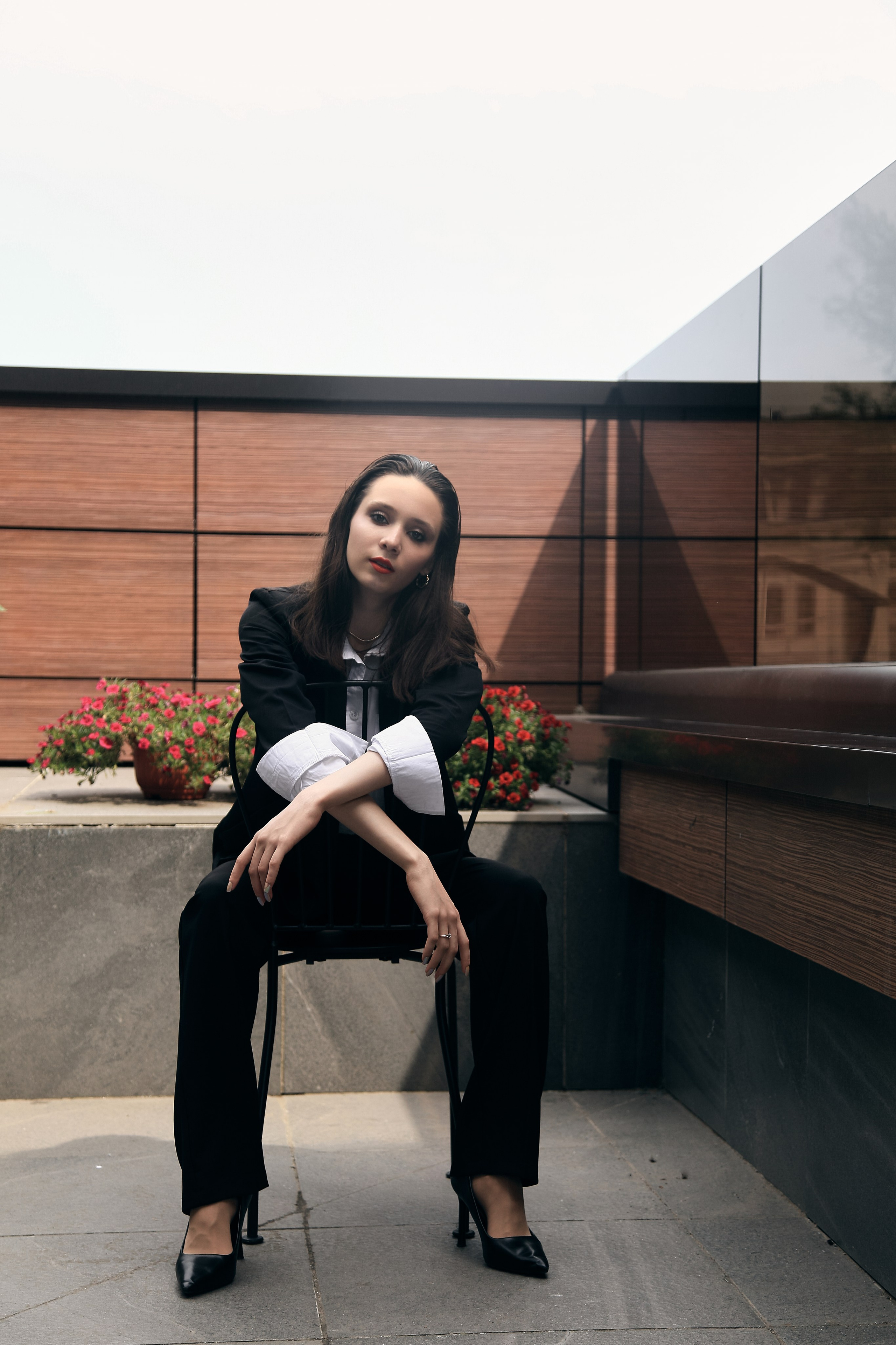 Красивая девушка с красными губами в чёрном деловом стиле с белой рубашкой сидит на стуле