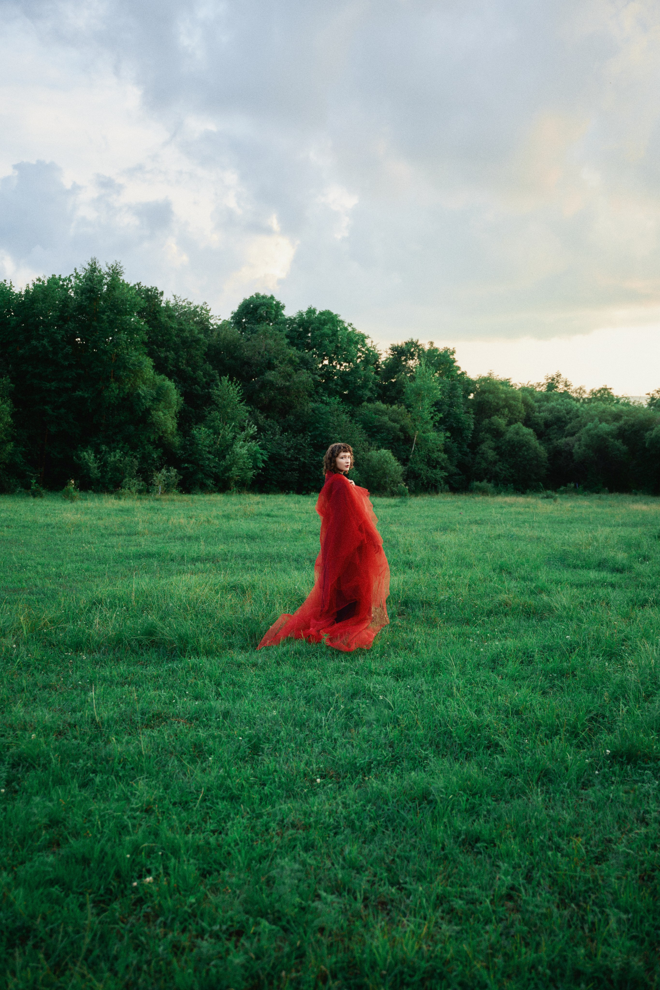 портрет девушки в красном на фоне поля и леса
