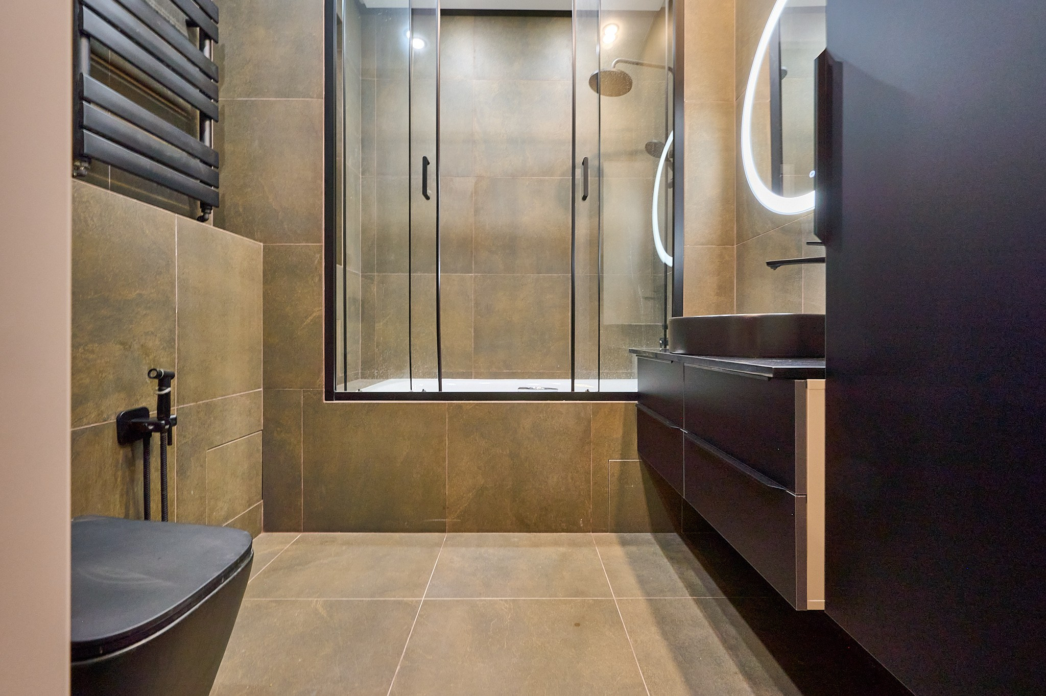 ванная комната темные полки с раковиной бежево коричневые оттенки круглое зеркало с подсветкой душевая кабина