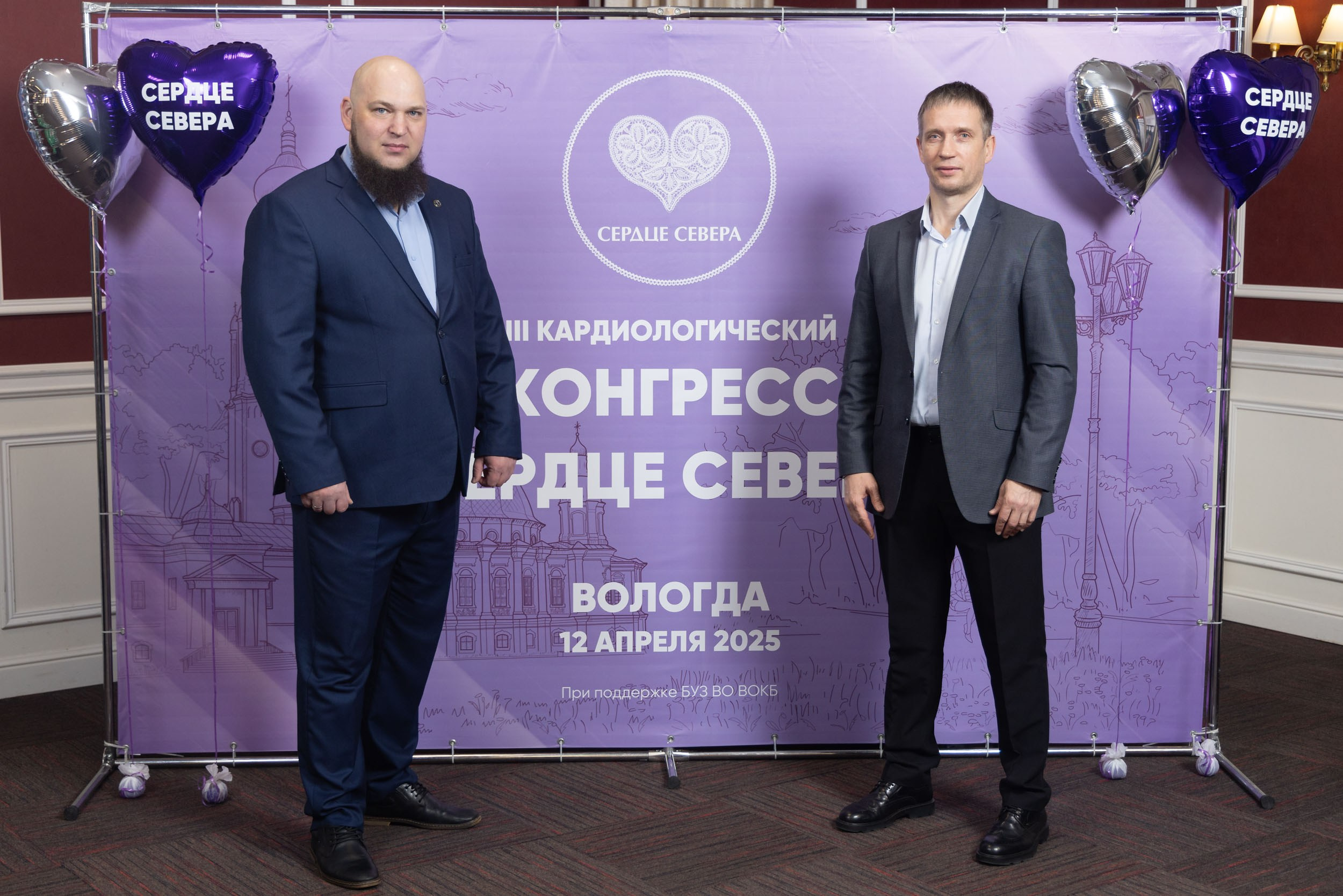 Два мужчины у фиолетового  банера стоят.