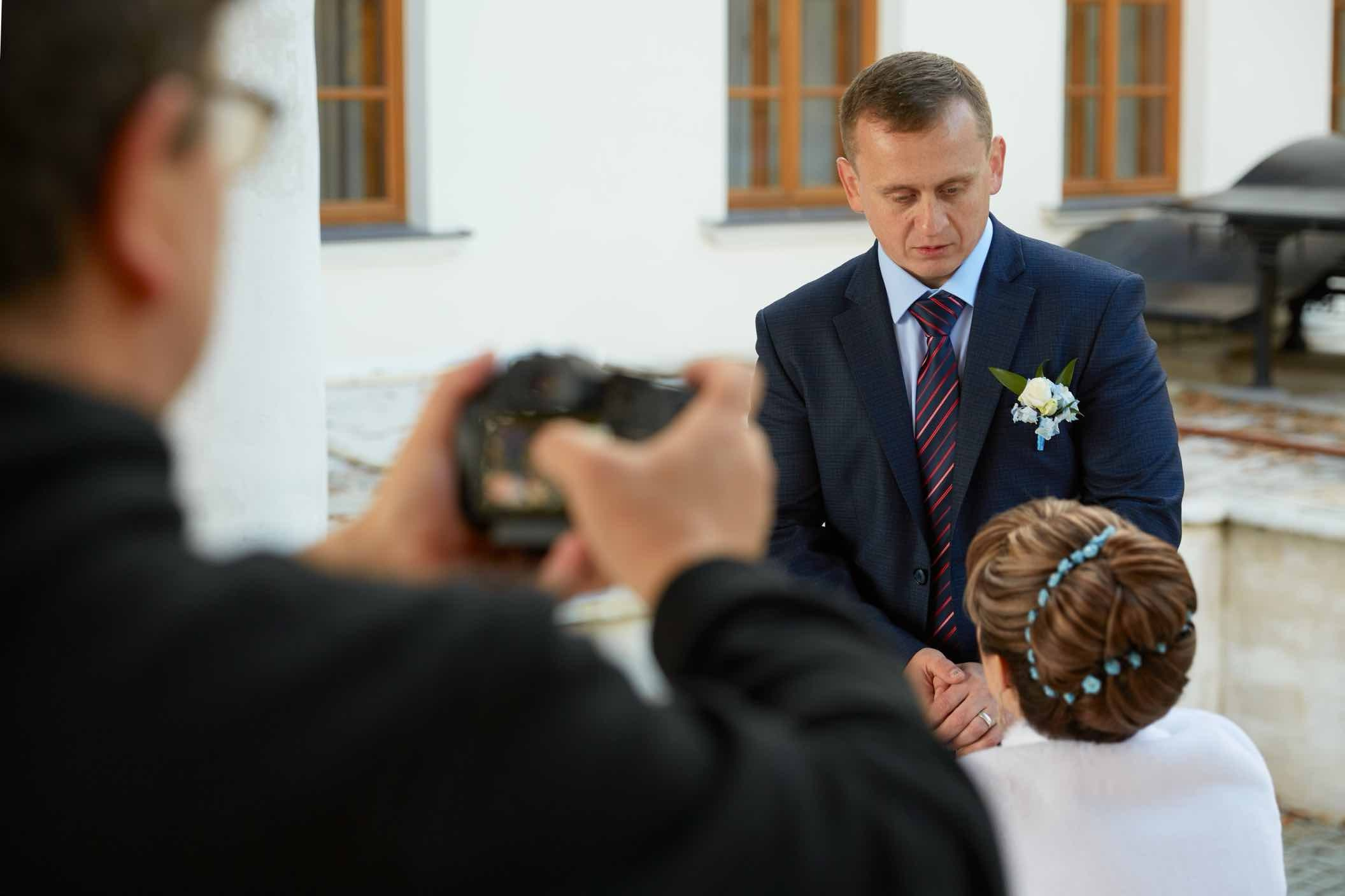 Оператор с камерой в руках снимает жениха и невесту на свадебной прогулке