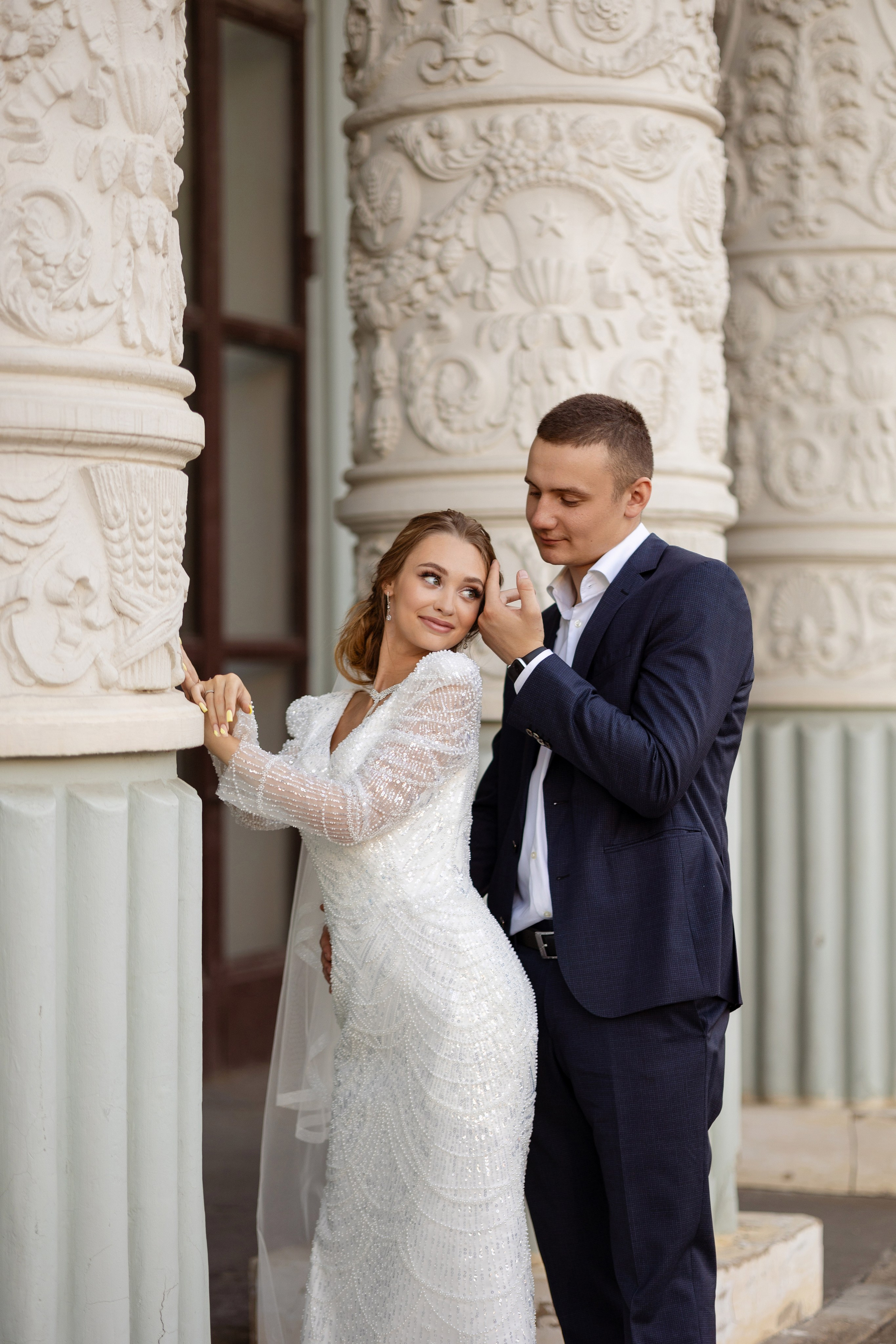 Меж тех же колонн молодые. жених гладит по щеке невесту.