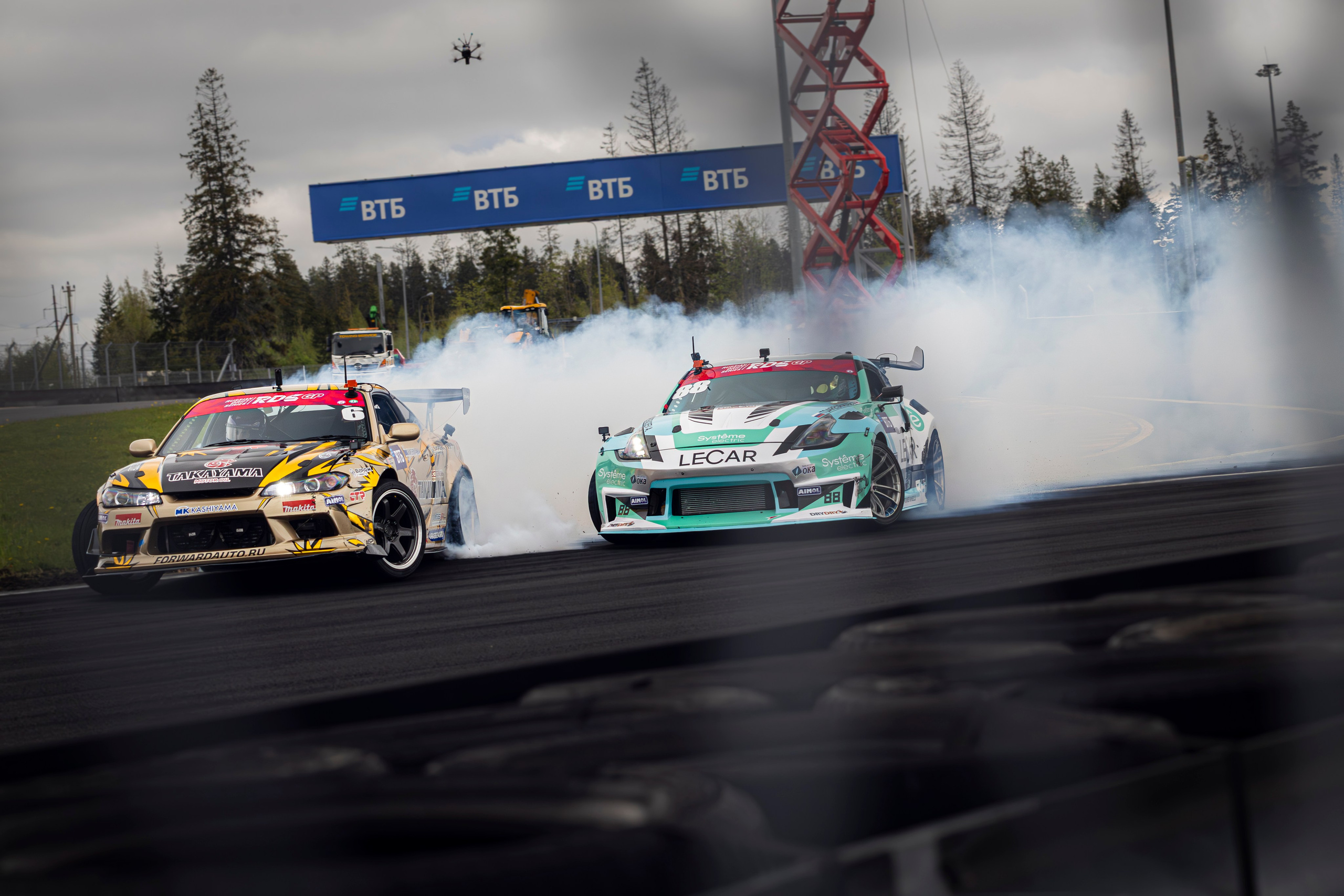 Два автомобиля идут в парном заезде, почти соприкасаясь бортами.