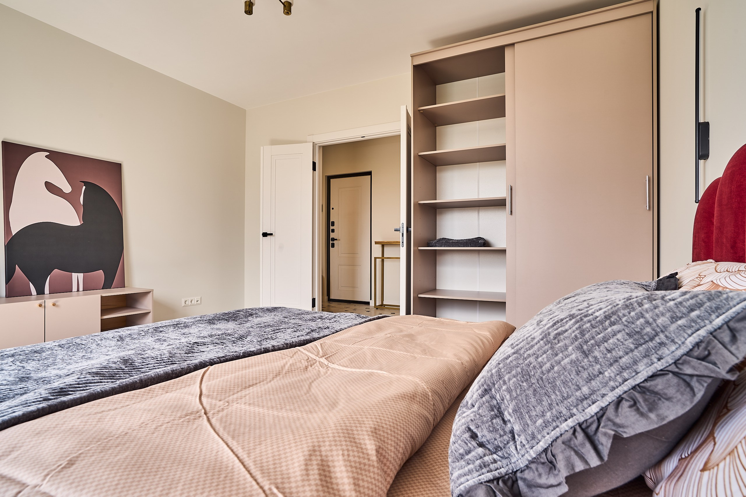 Интерьерное фото с подушками на переднем плане, шкафом и открытой в коридор дверь на заднем плане