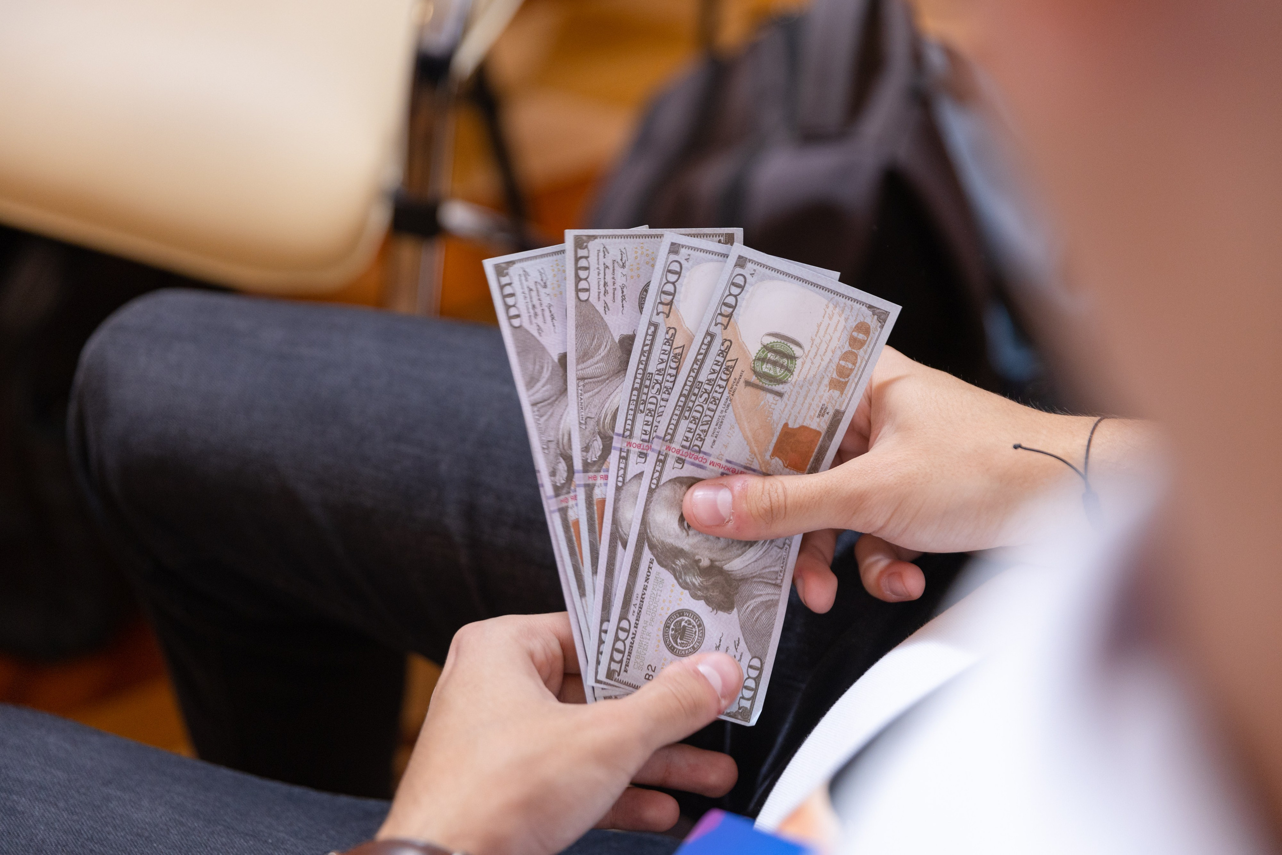 На переднем плане руки держащие веером денежные купюры.