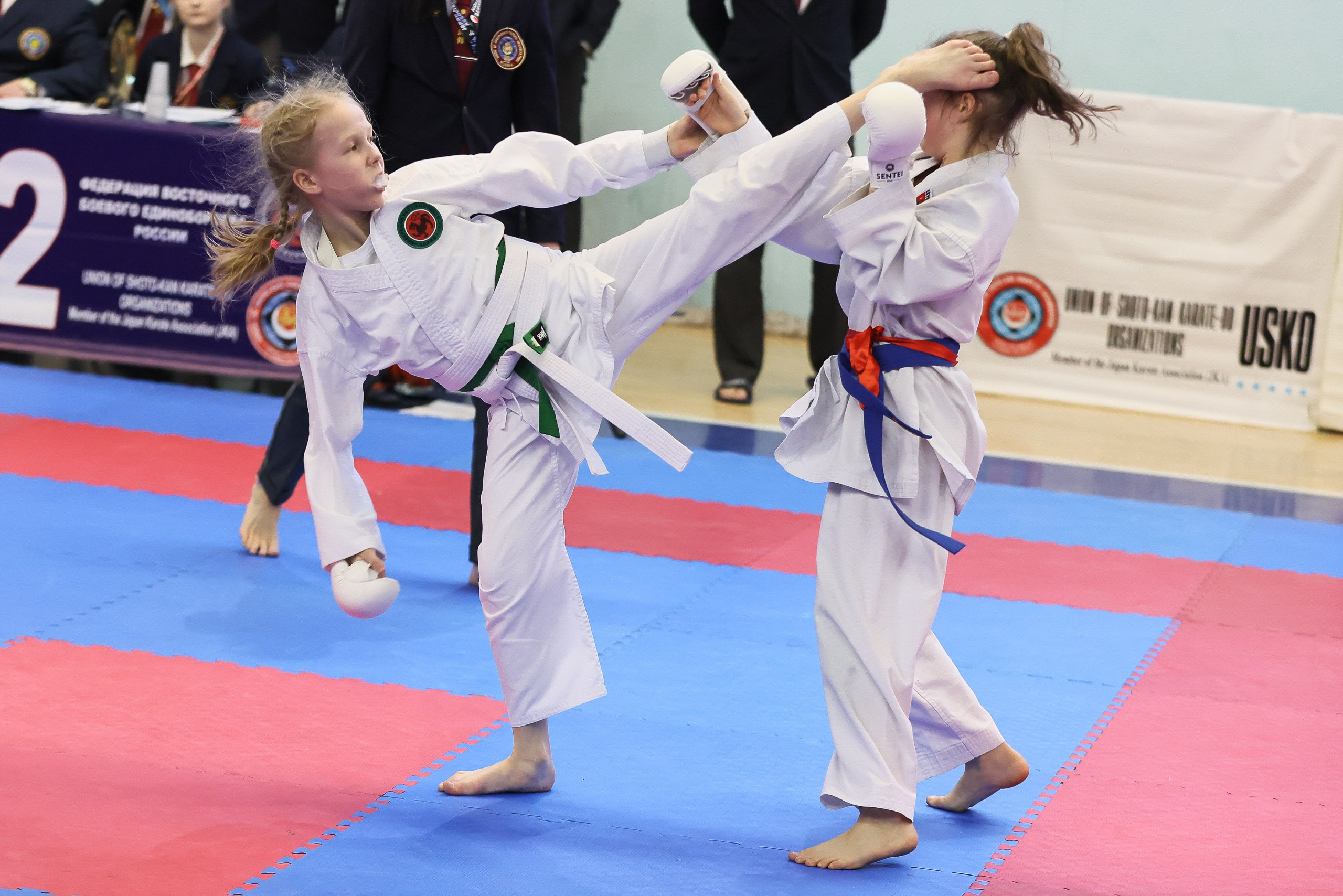 Девочка карате наносит удар ногой в голову в кумите