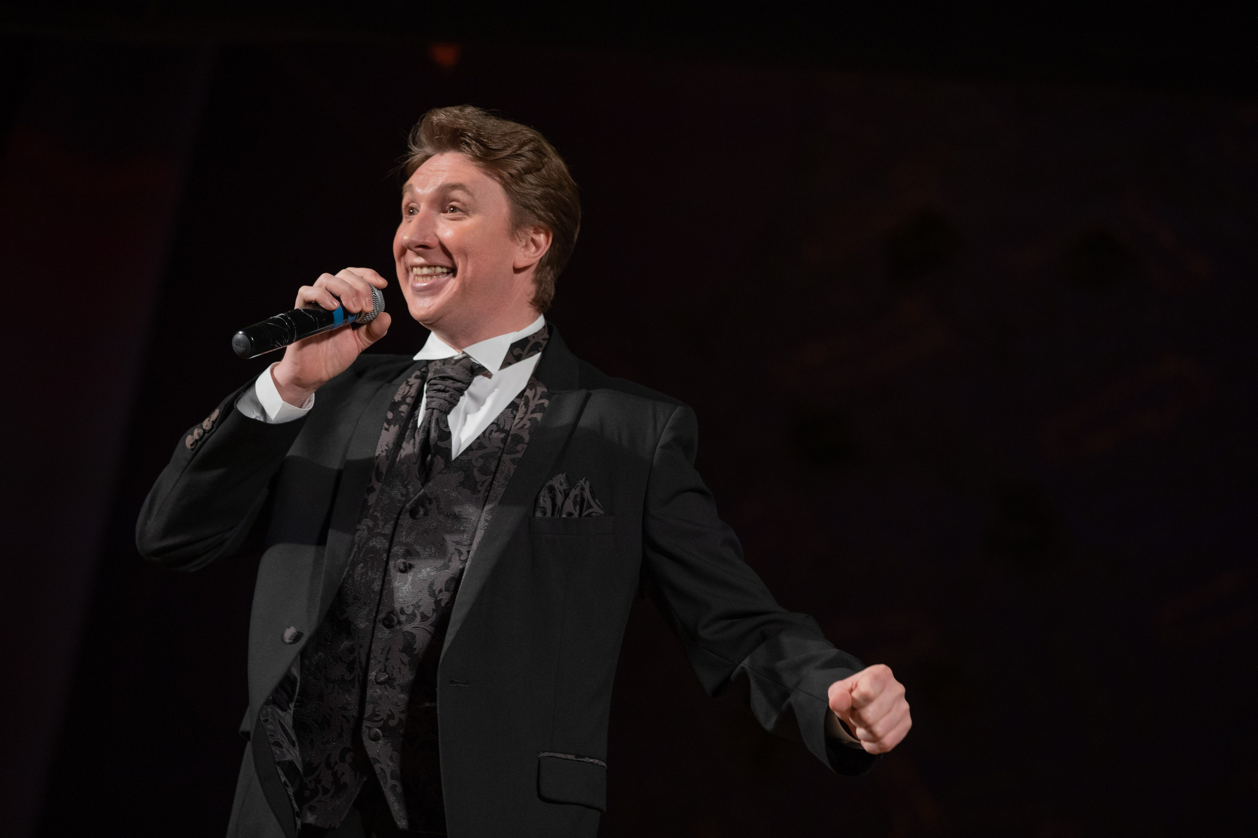 Артист в костюме поет на сцене.