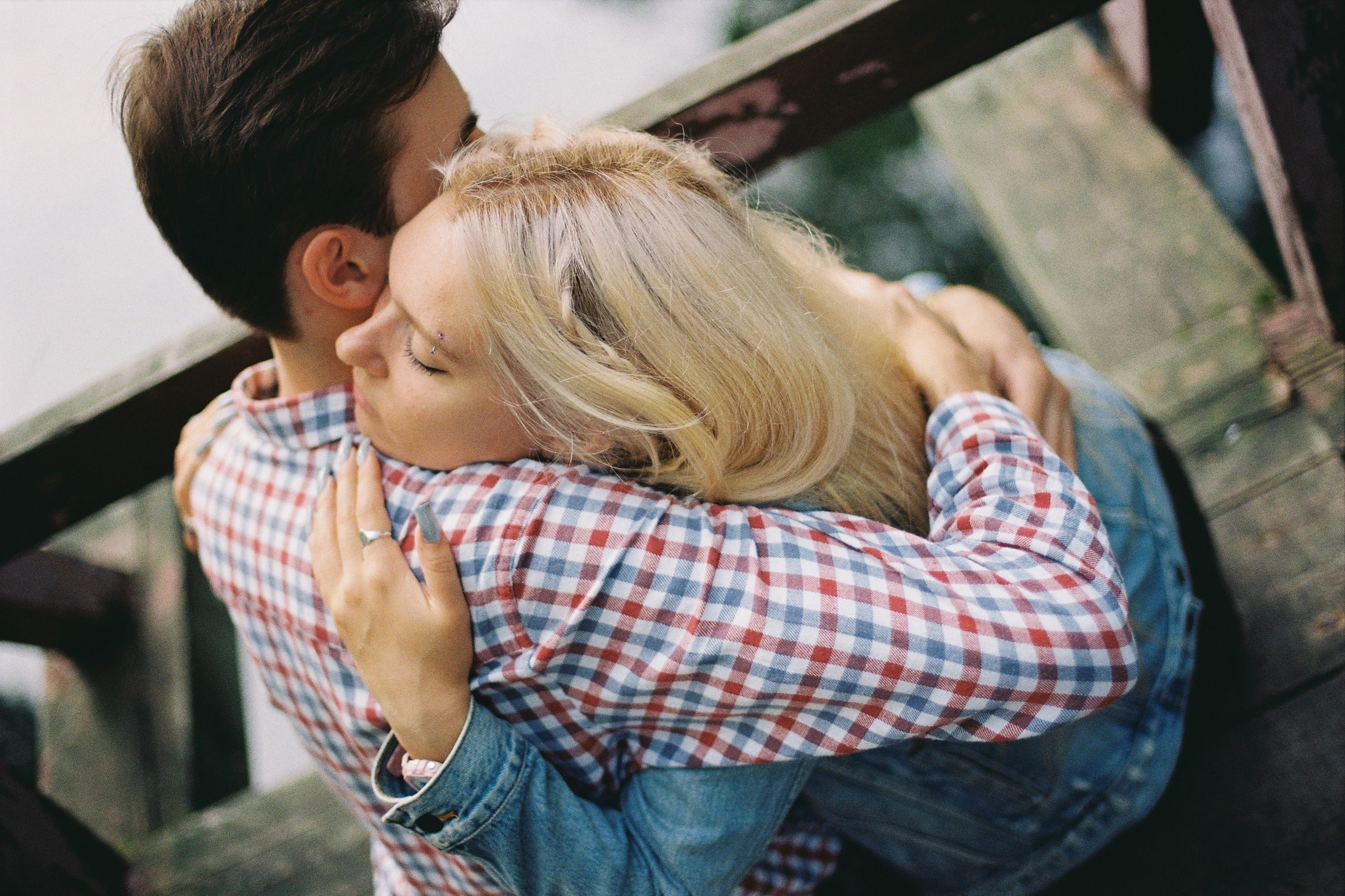 Парень с девушкой обнимаются, сидя на мосту у пруда