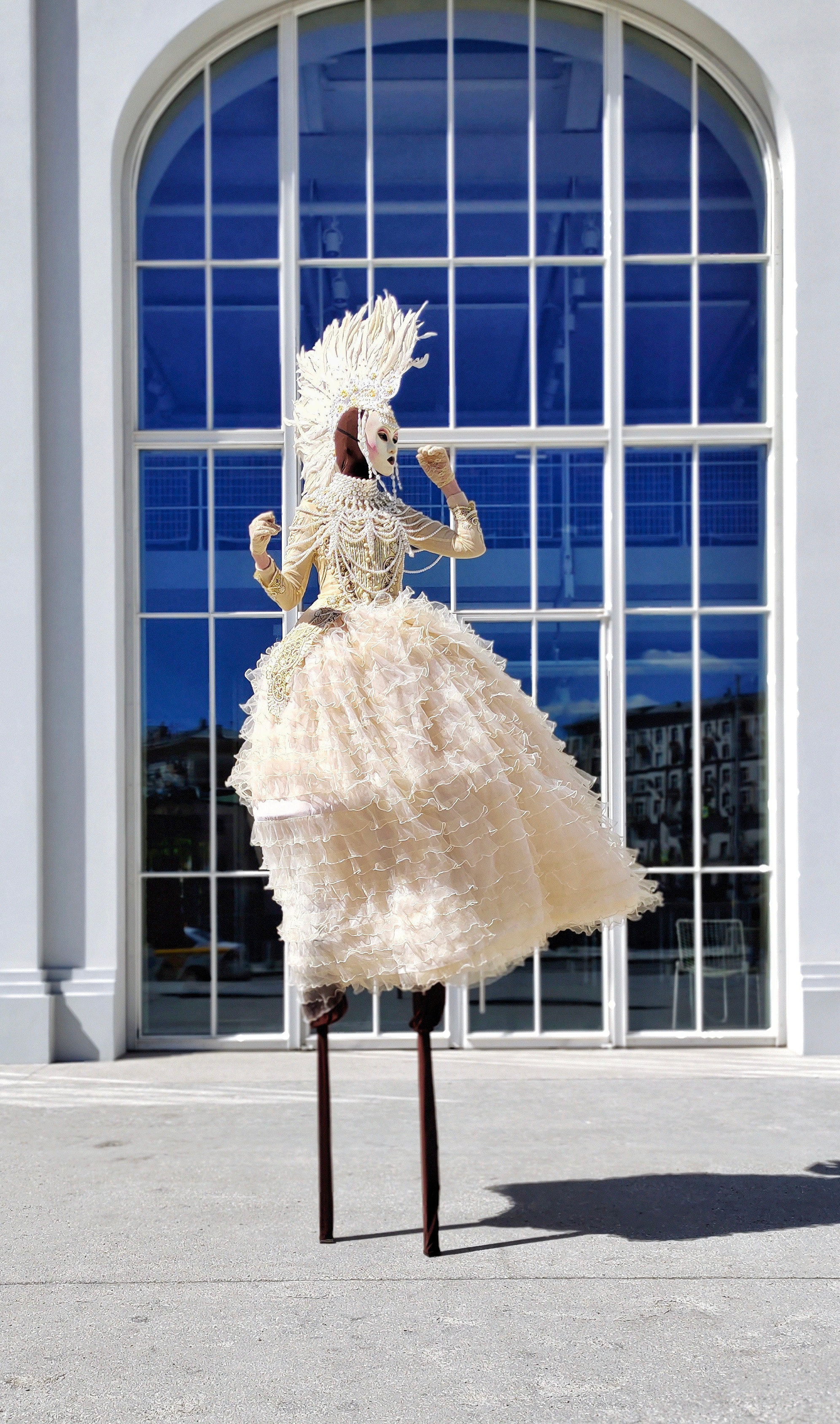 Ходулисты в светлых нарядах на раусе на мероприятии.