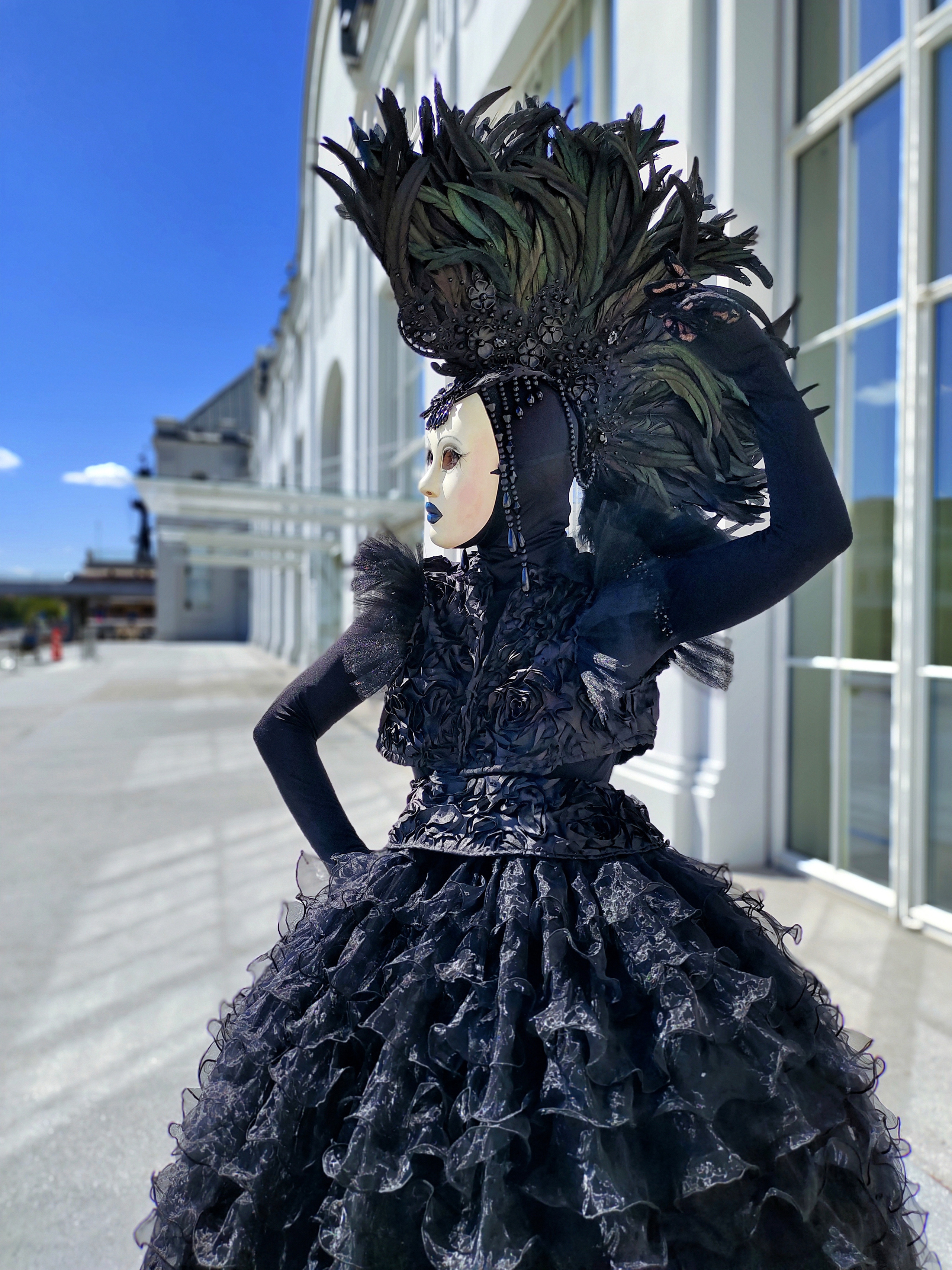 Девушка мим с ирокезом на голове из перьев встречает гостей на свадьбе.