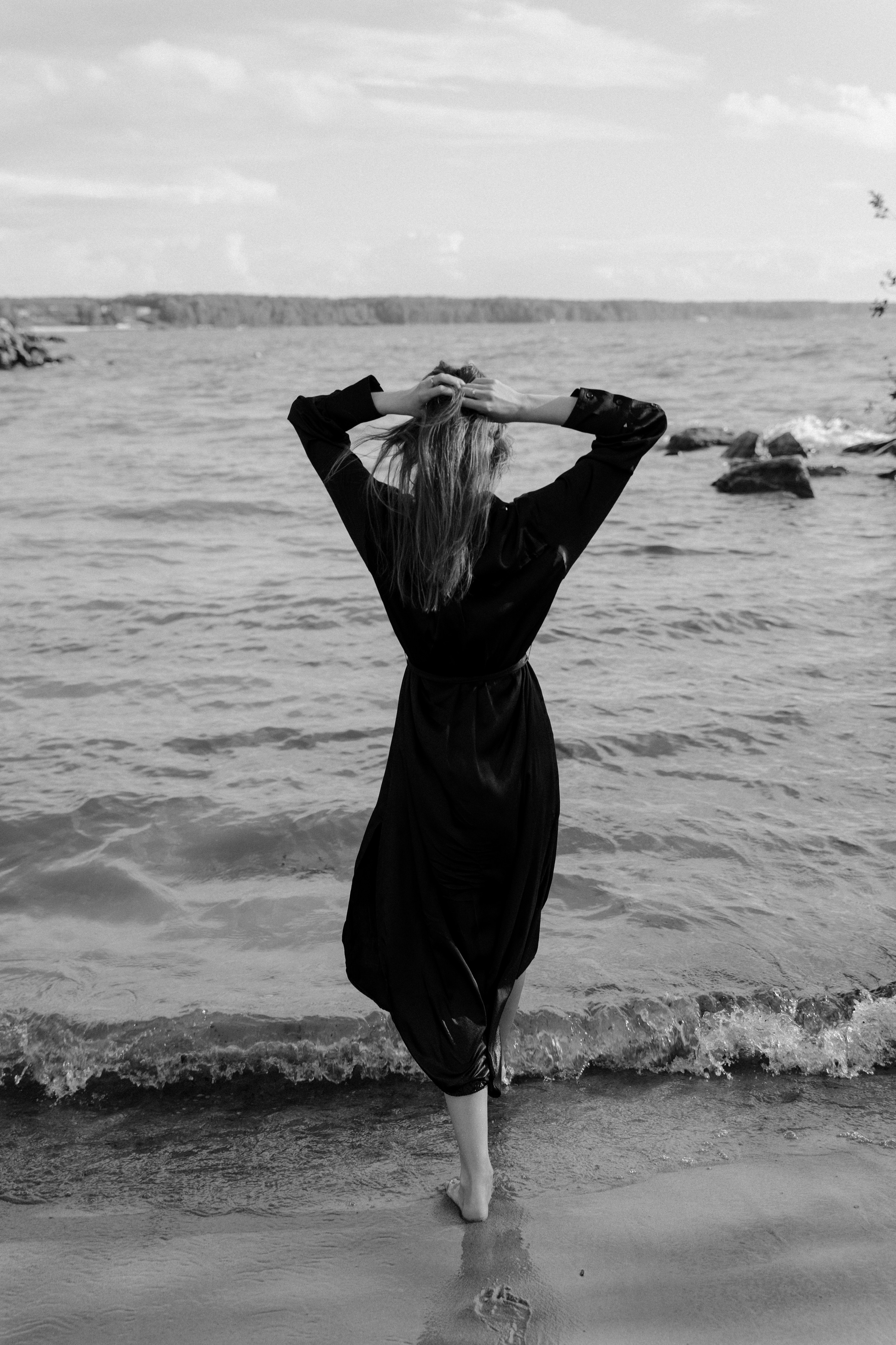 Девушка на берегу реки летом заходит в воду