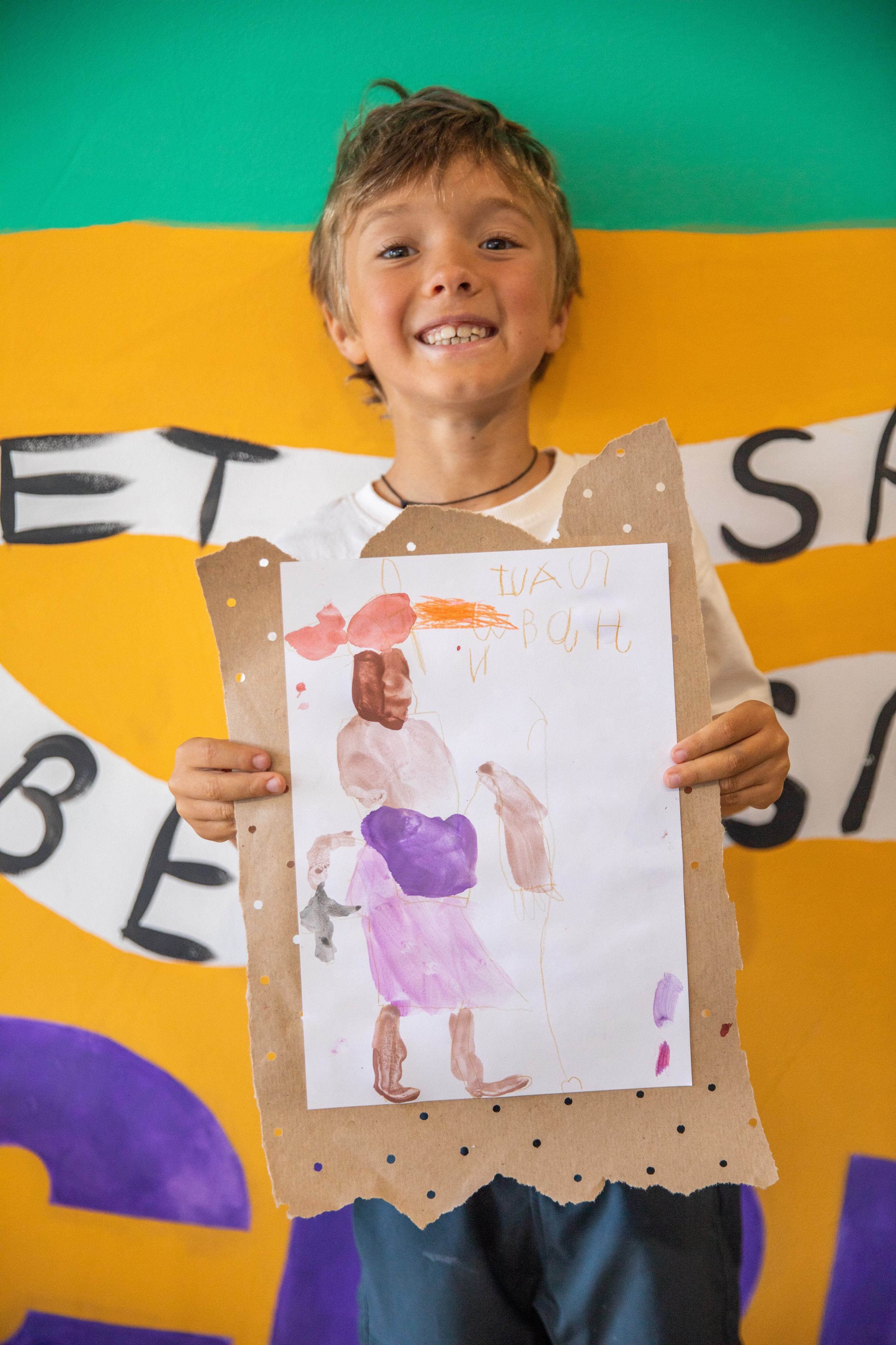 The joyful boy smiles and shows his drawings