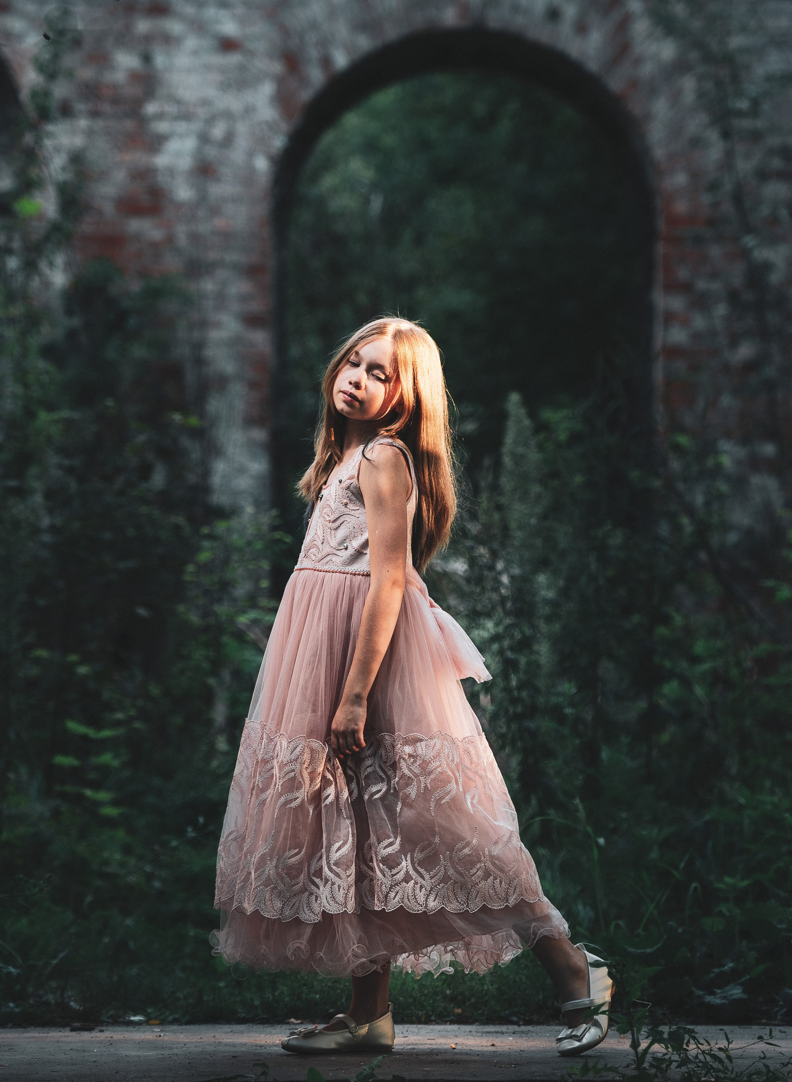 Девочка в красивом платье на фоне кирпичной стены