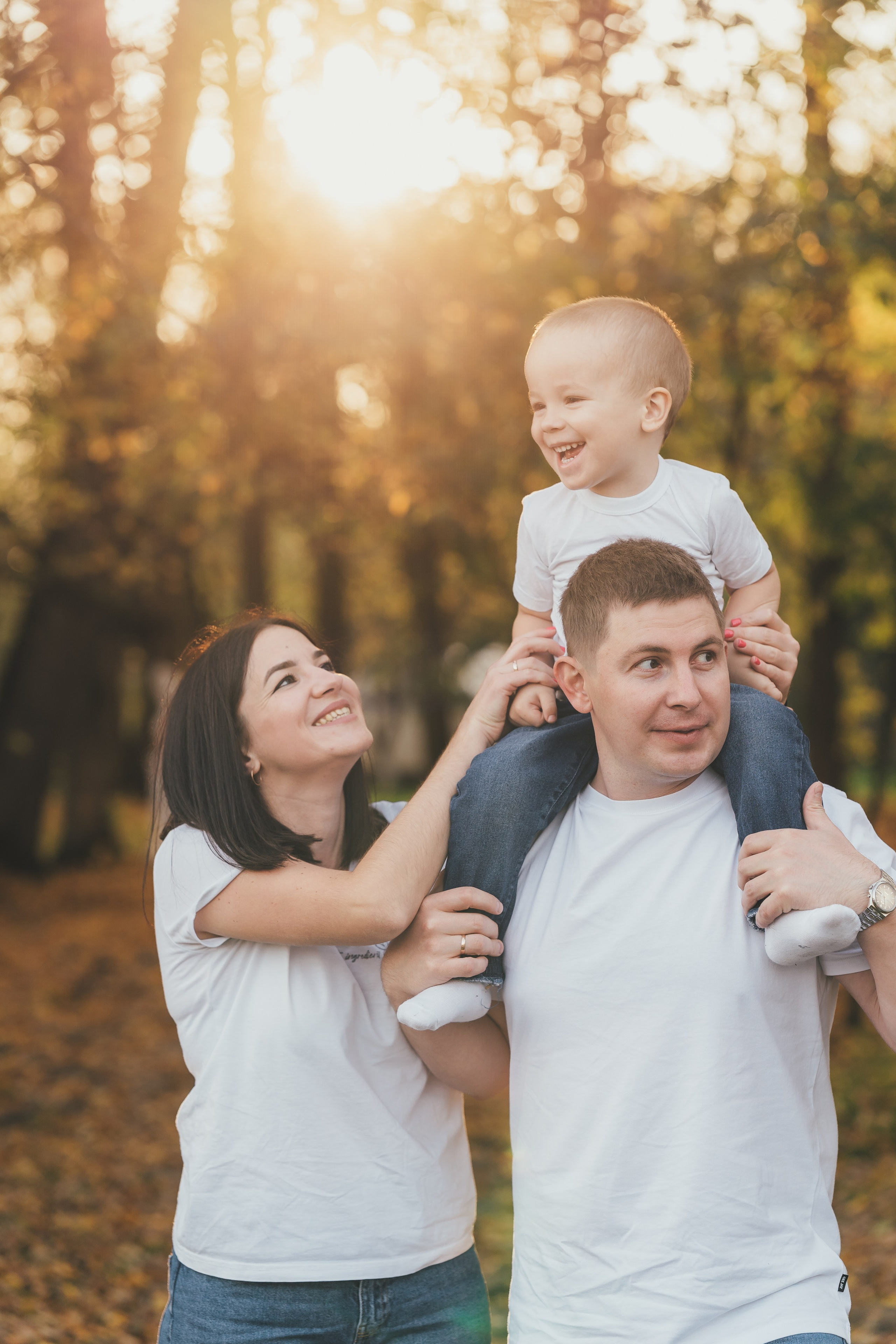 Папа посадил сына на плечи, мама обнимает папу и придерживает сына