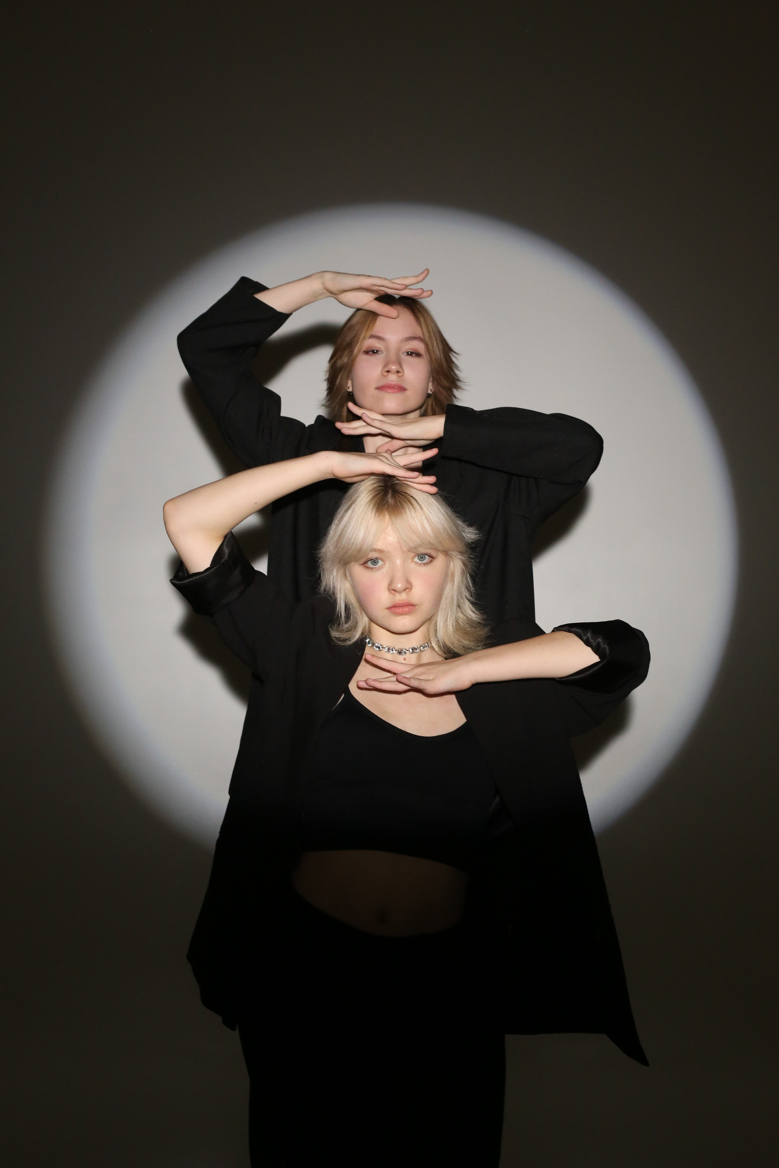 Фотосессия «Геометрия»: две девушки в черных костюмах позируют в круге света