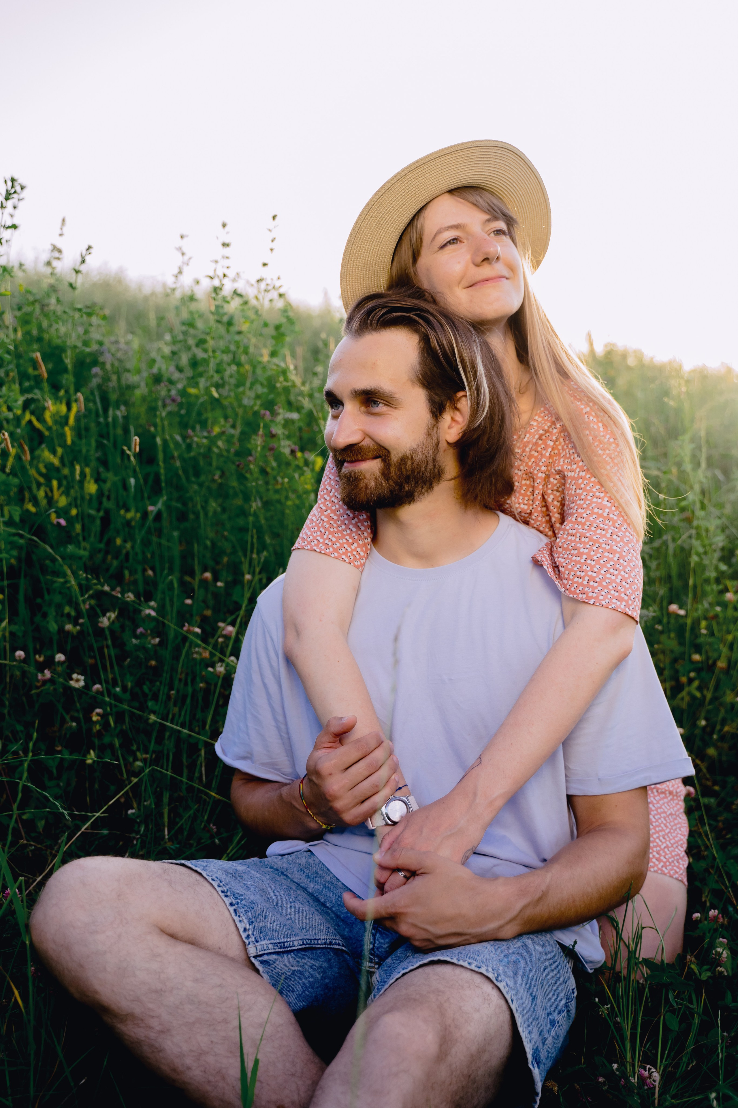 Фотоснимок обнимающие девушка парня со спины в закатном солнце