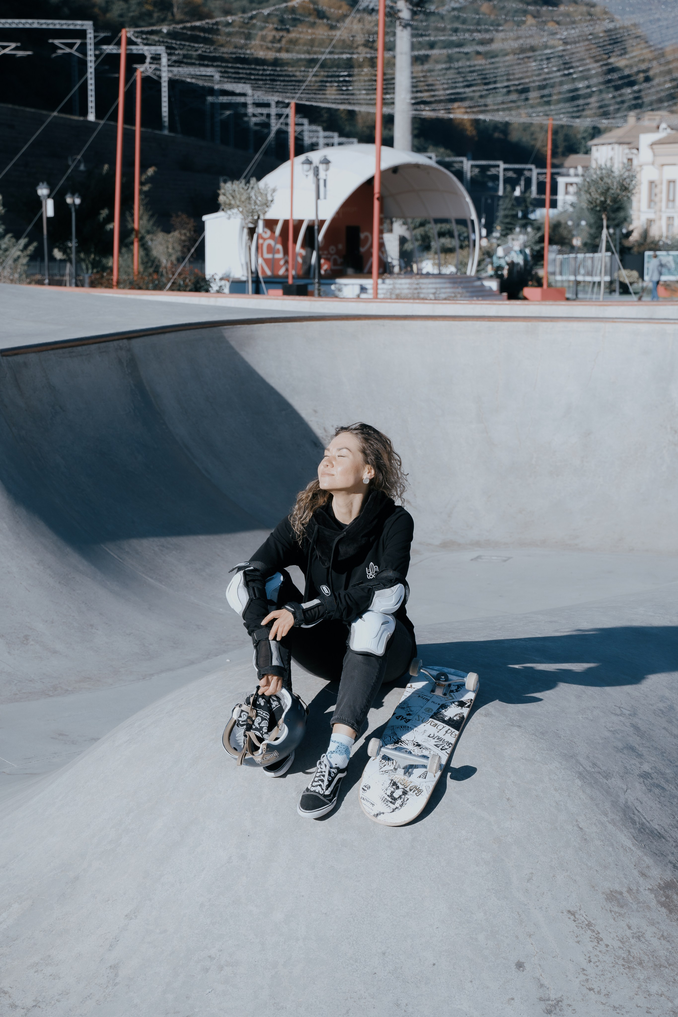 Снимок девушке сидящей в центре скейт парка 