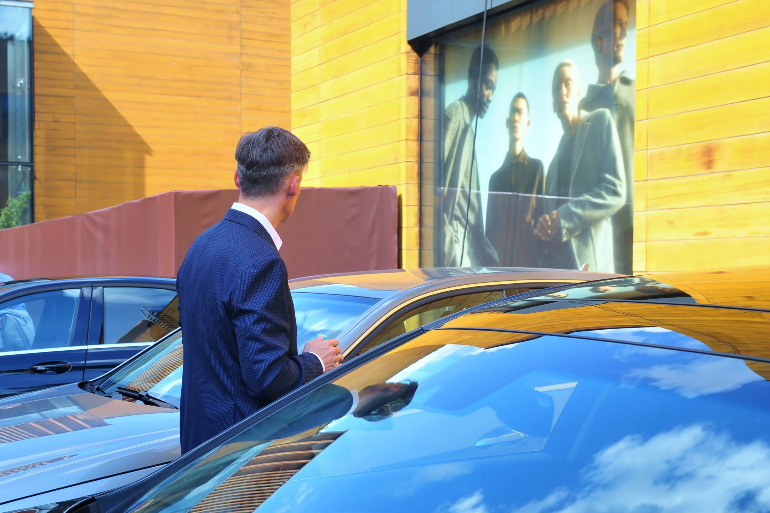 Свадьба в ЗАГСе Барвиха Luxury Village летом, жених стоит среди чёрных машин и ждет невесту