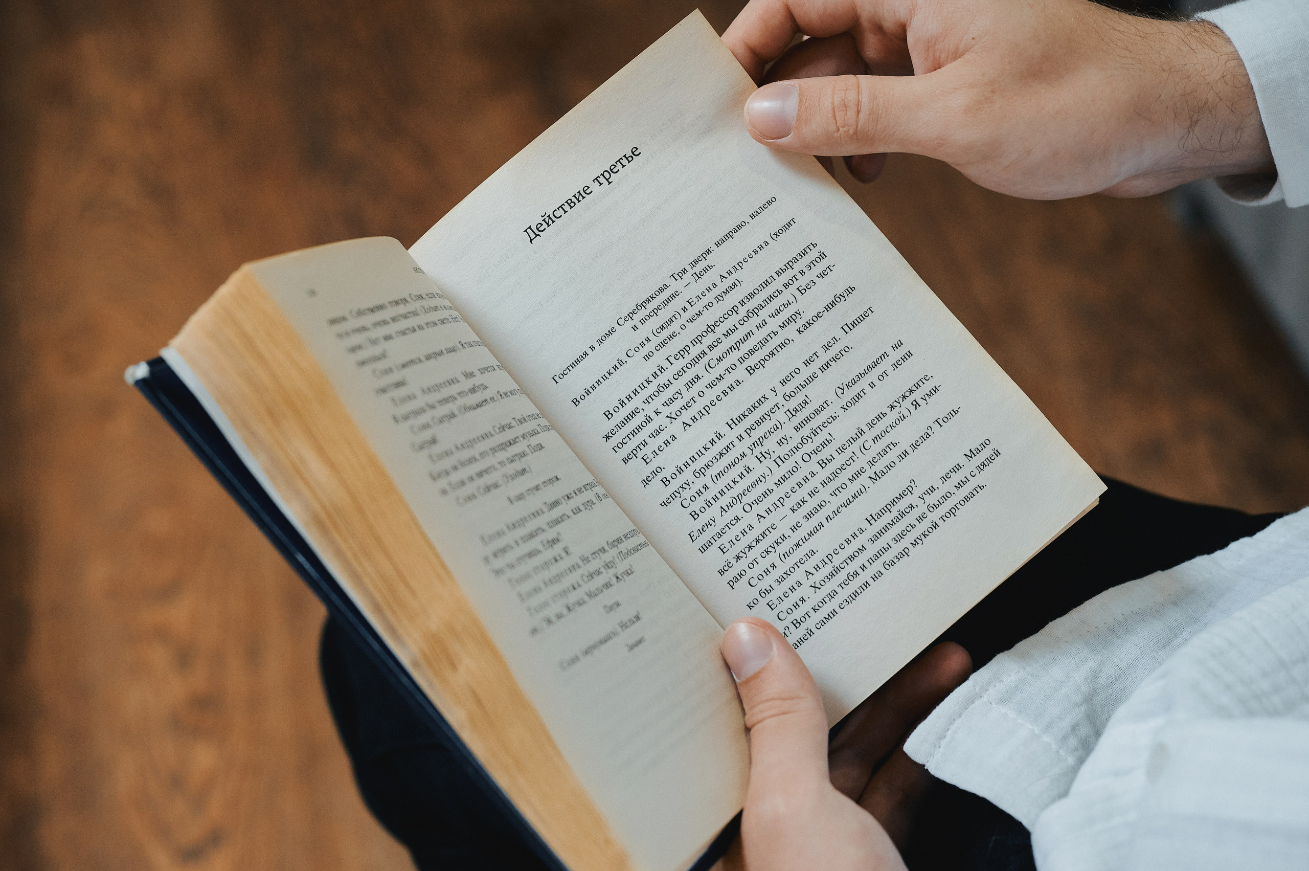 Мужчина держит раскрытую книгу, видна страница с заголовком «Действие третье»