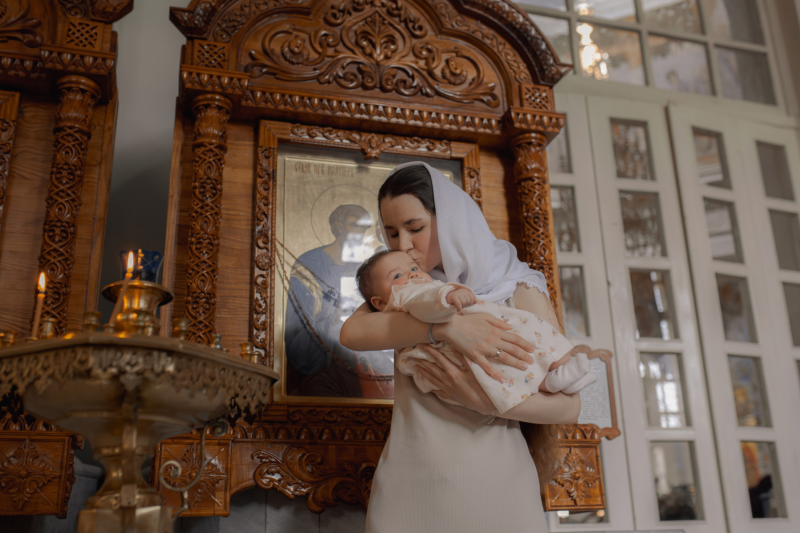 мама целует малышку перед совершением крещения в Ташкенте