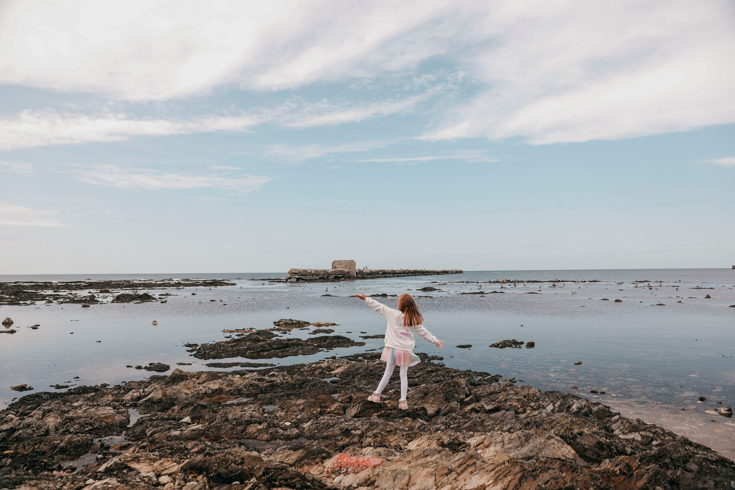  красивая маленькая девочка в радужном платье чтоит на берегу татарского залива осенью