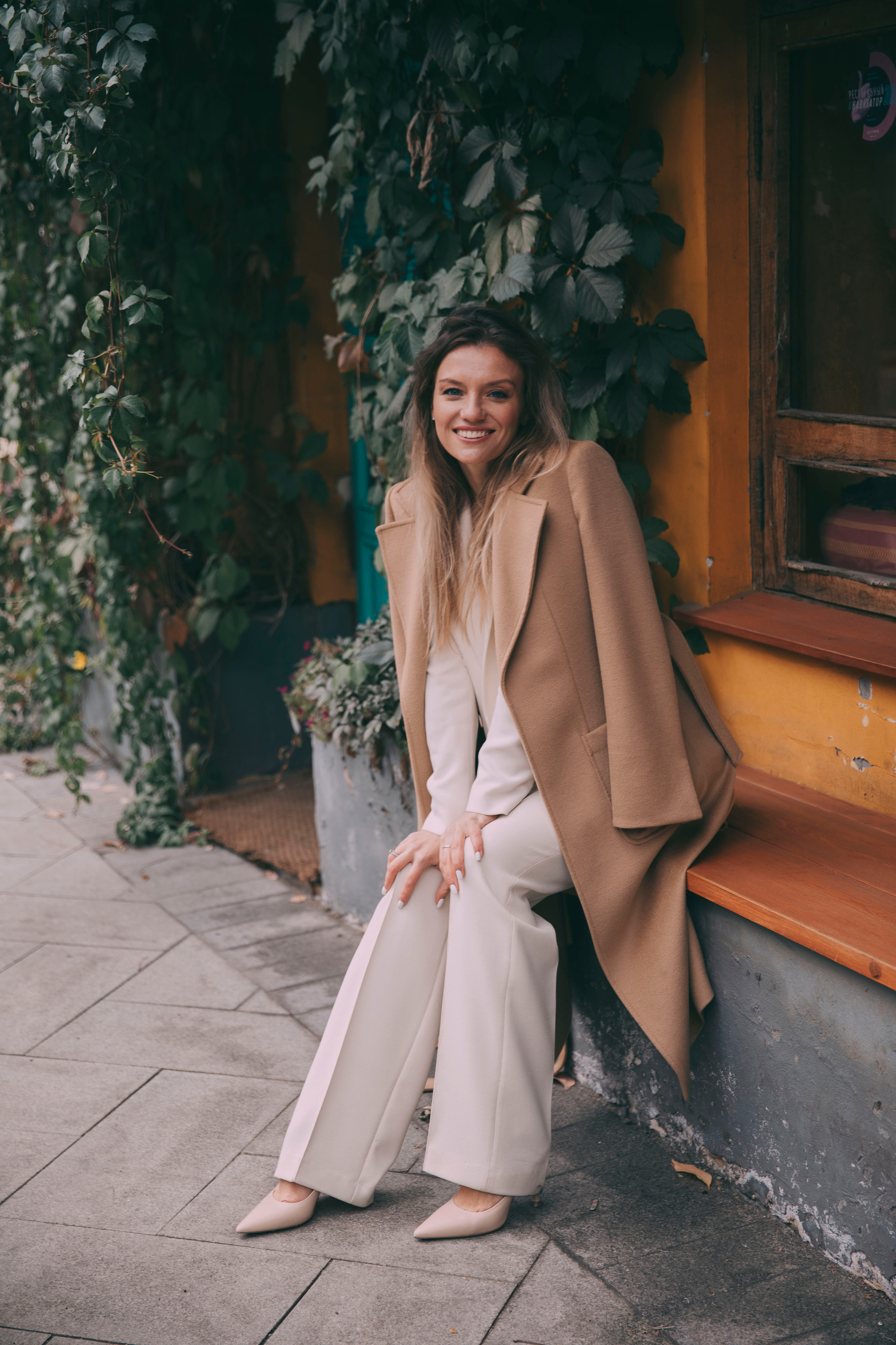 красивая высокая блондинка в белом костюме и бежевом пальто на фотопрогулке по Москве