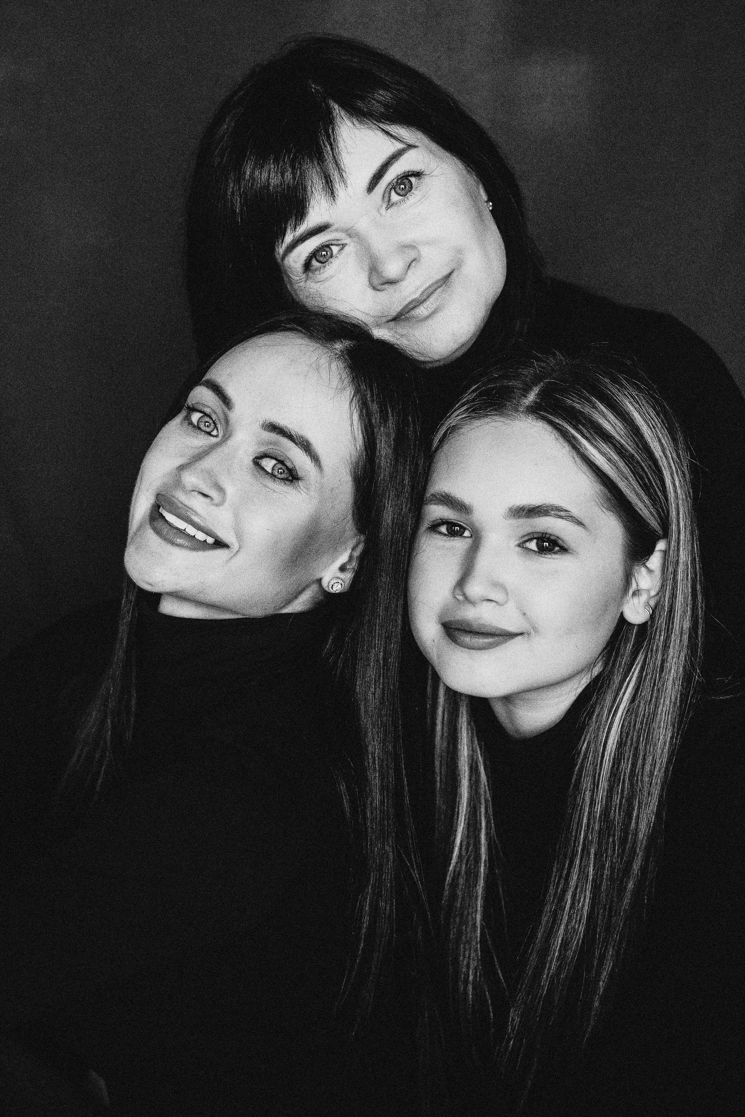 Красивая мама   в черной водолазке со своими красивыми взрослыми дочками на фотосессии