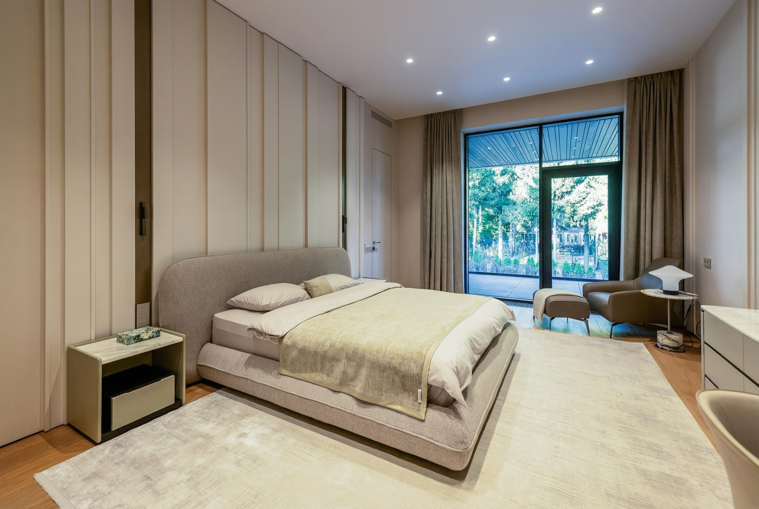 Интерьер мастер-спальни с панорамным выходом на террасу, дизайнерской кроватью букле и архитектурным стеновым панно, проект Валерии Котович в Подмосковье.