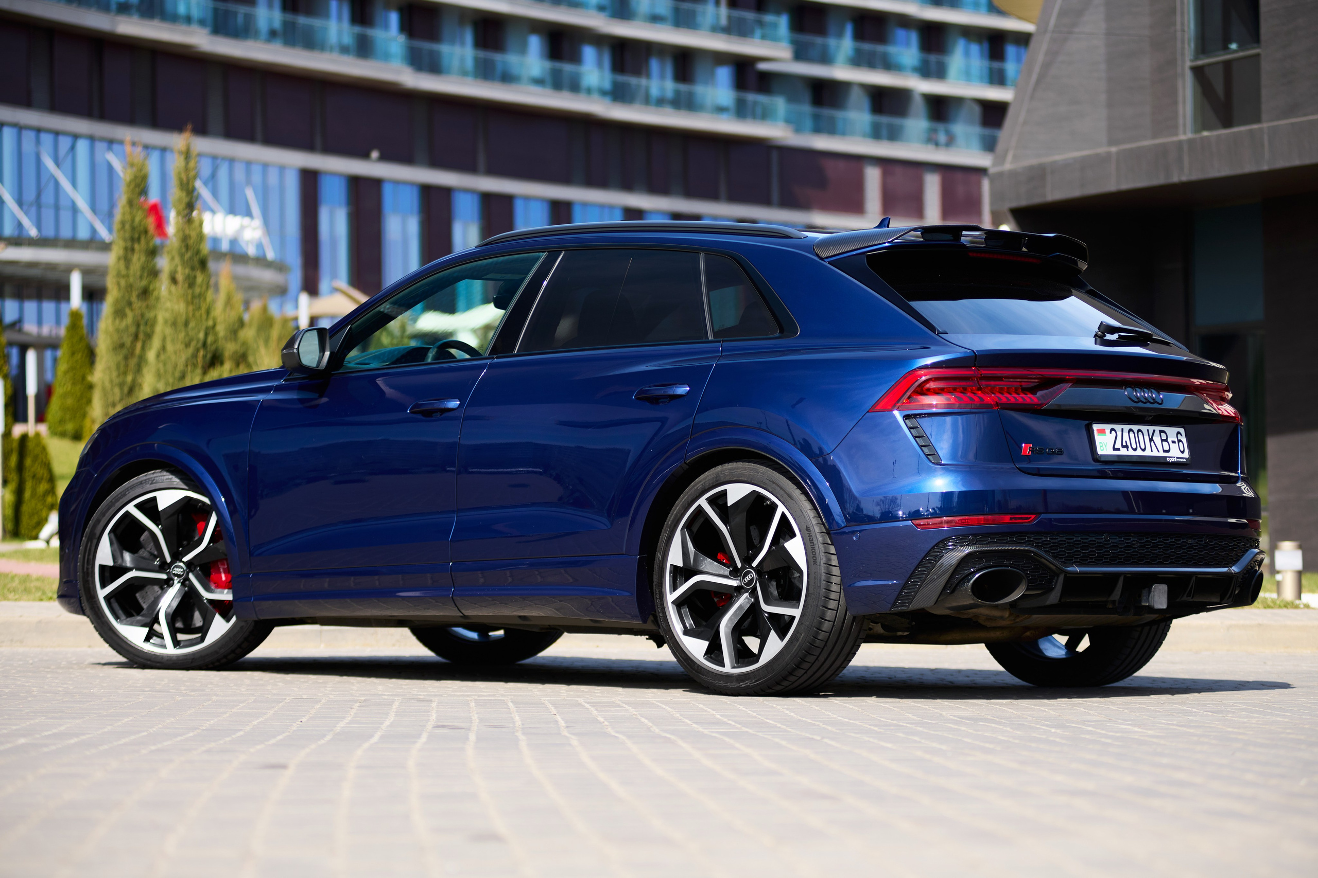 Audi RS Q8 с заднего левого ракурса на фоне современного здания