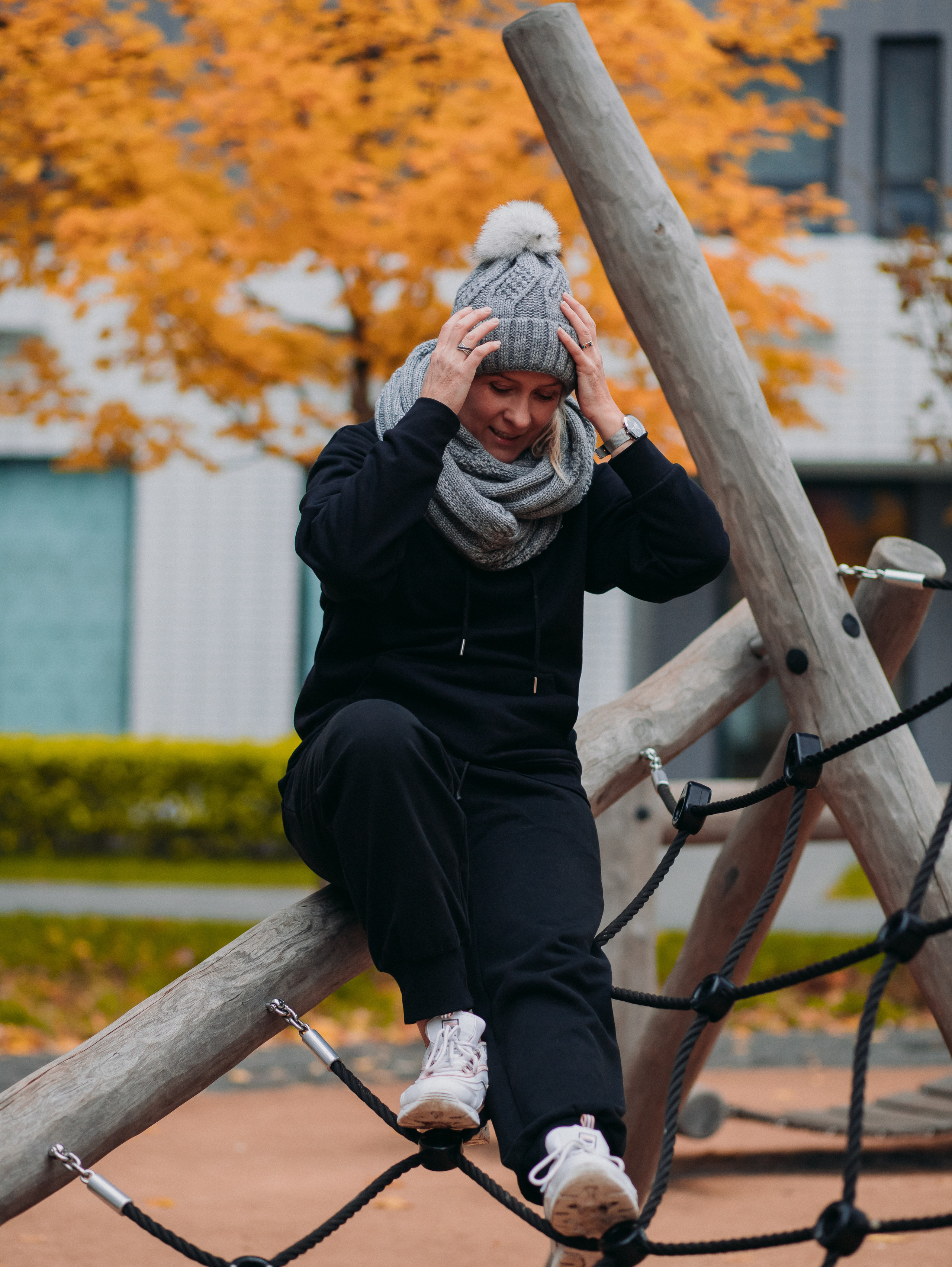 Девушка в шапке и в черном костюме на детской площадке