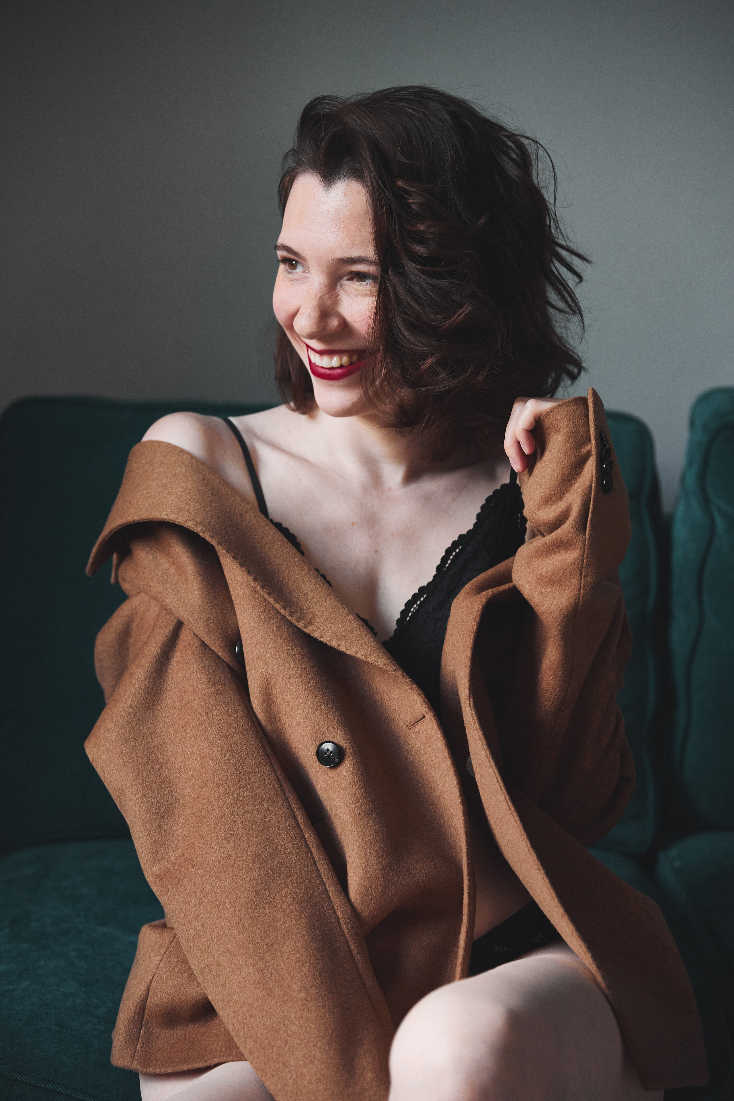 Красивая девушка с темными волосами, в песочном пиджаке,  на диване